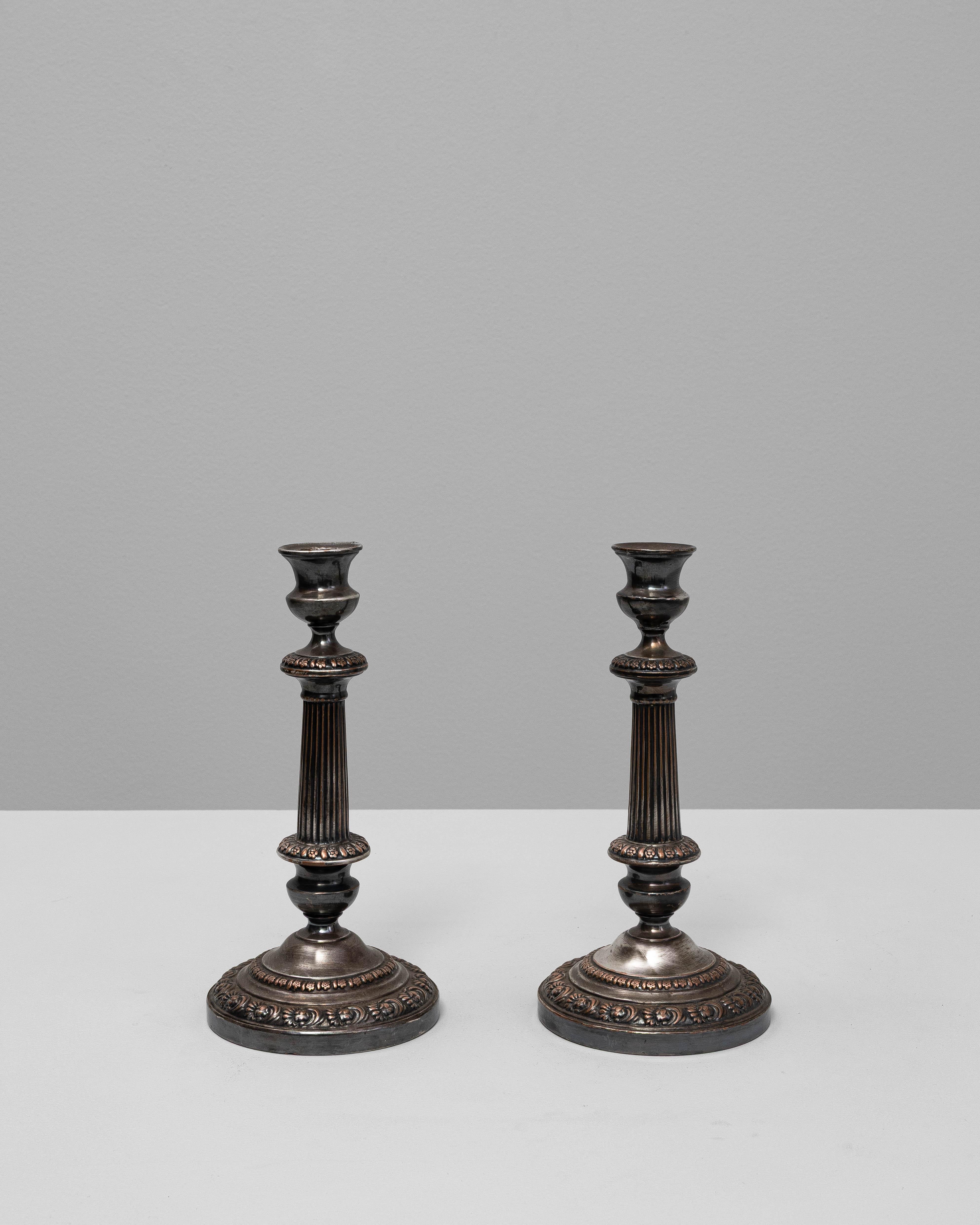 Questa elegante coppia di portacandele francesi del XIX secolo è un esempio di raffinato design neoclassico. Ogni pezzo è caratterizzato da un gambo a colonna scanalata che poggia su una base circolare ornata da motivi floreali e perline. La