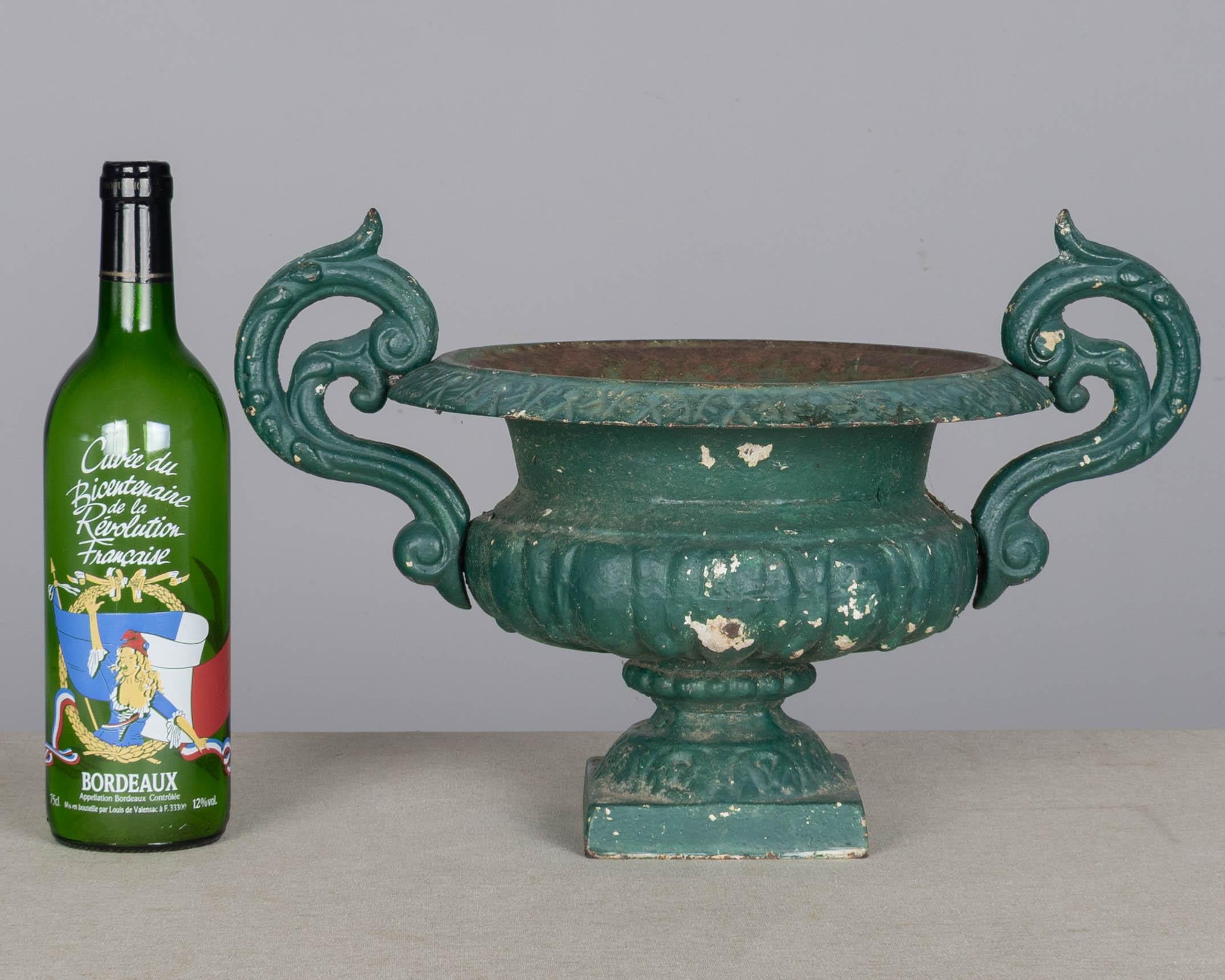 A pair of 19th century French small cast iron garden urn planters with pedestal base and scrolled handles. Weathered green painted patina with some rust and paint loss. Circa 1880-1900.
Overall Dimensions: 15.5