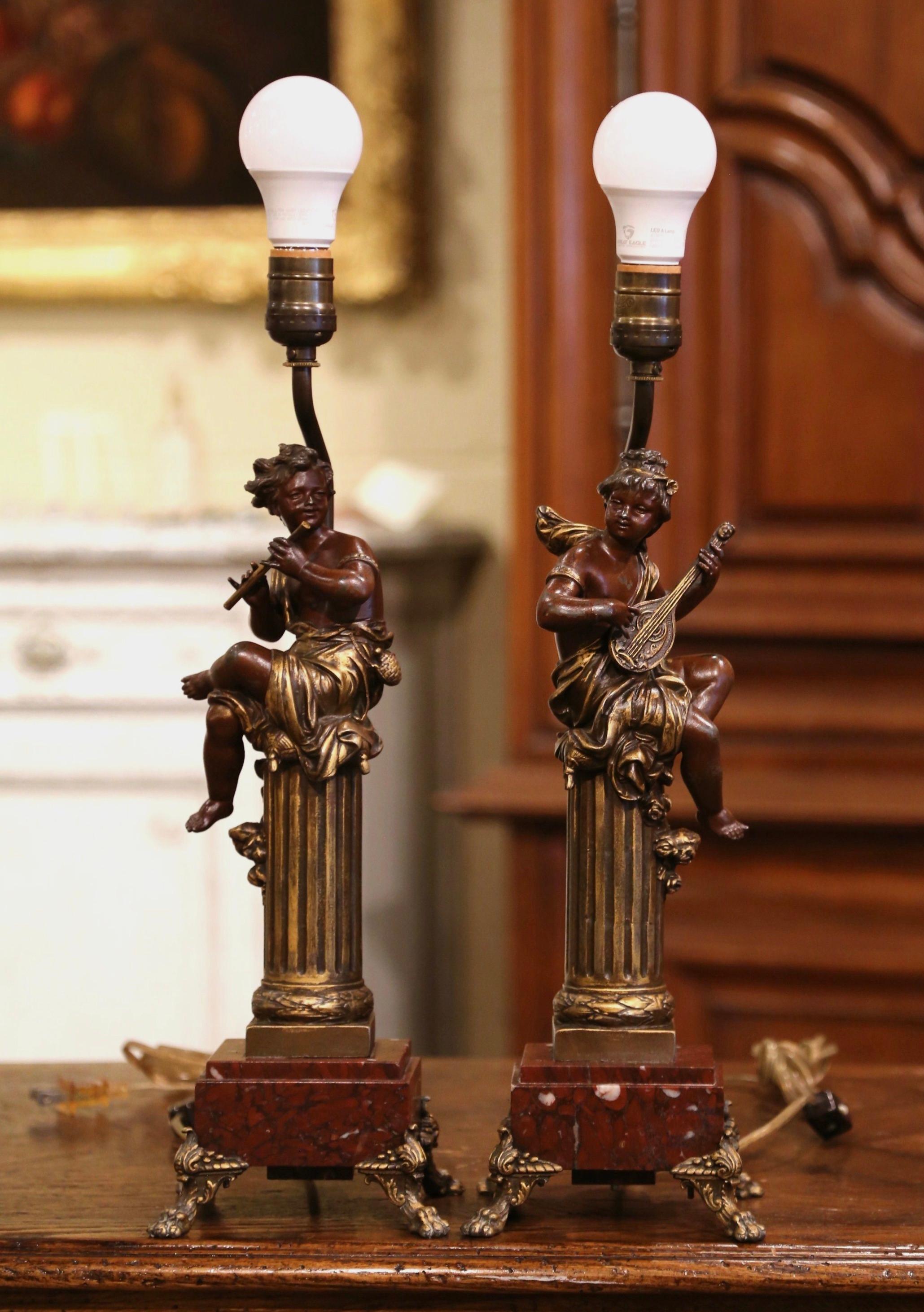 Décorez un bureau ou un salon avec cette élégante paire de lampes anciennes. Fabriqué en France vers 1870, chaque luminaire repose sur une base carrée en marbre rouge, terminée par des pieds griffes. Les deux figurines, réalisées en étain,
