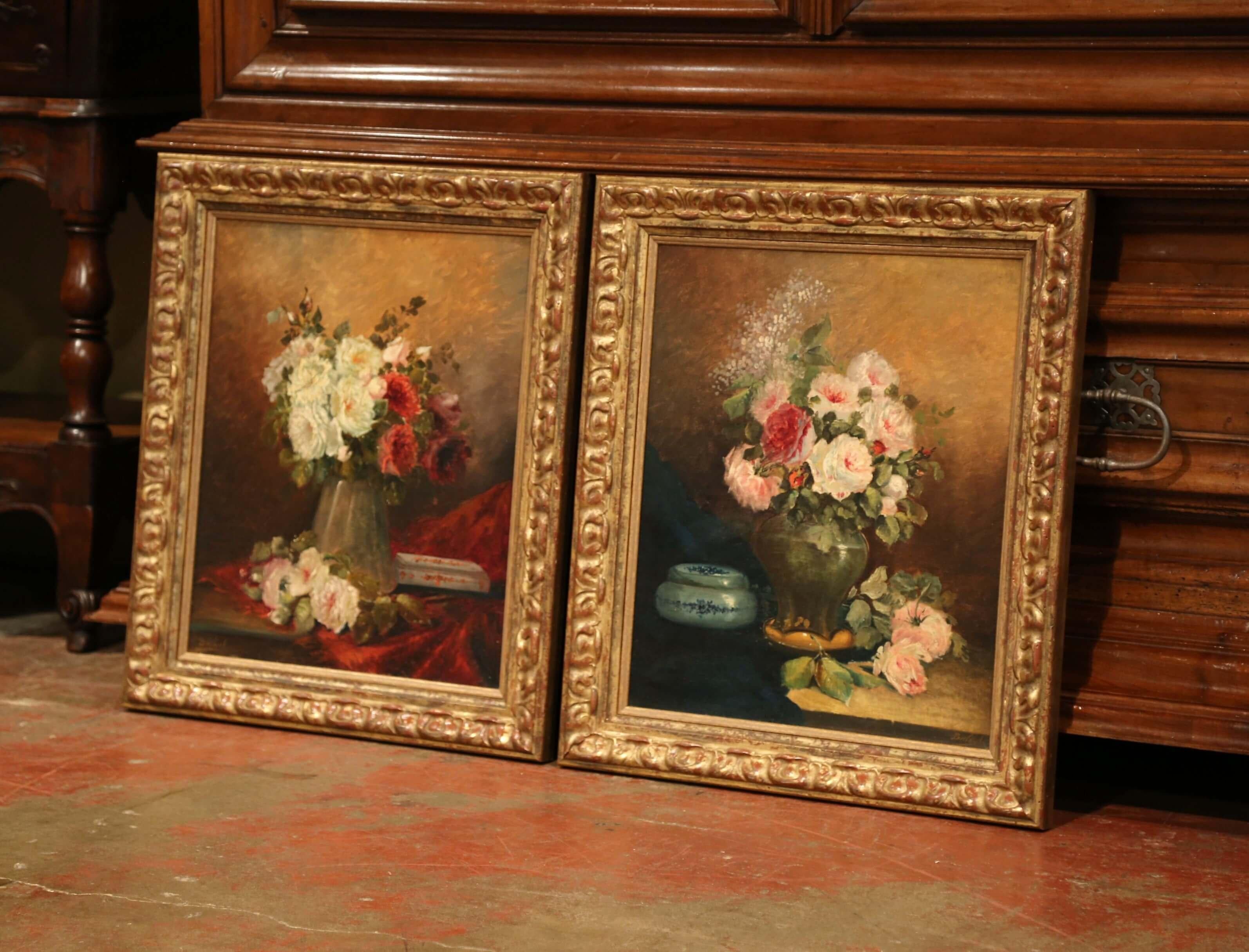 Invite color into your home with this traditional pair of antique, floral paintings. The paintings were crafted in France circa 1870 and are set in carved gilt frames. Each canvas features a vase on a table filled with colorful flowers. The