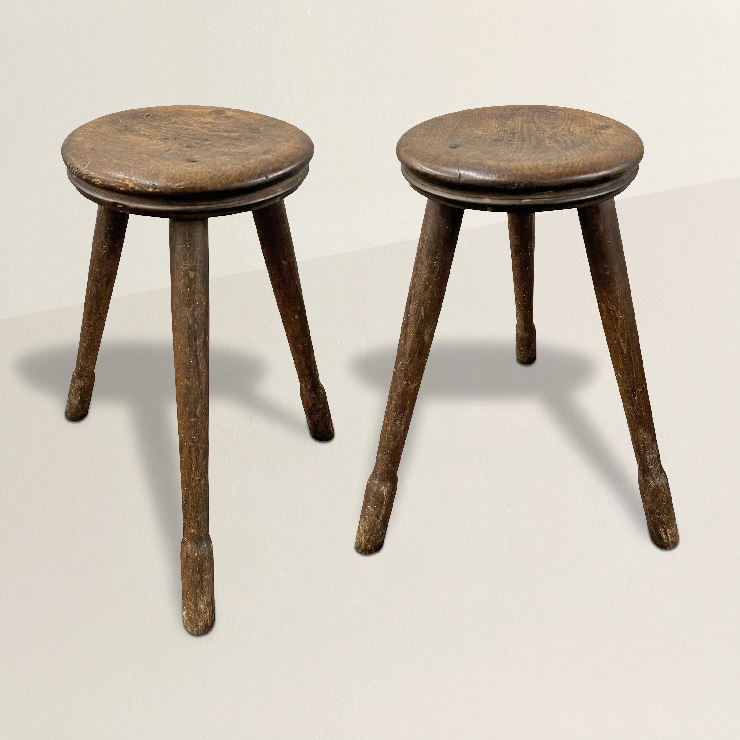 Ein Paar französische Hocker aus dem späten 19. Jahrhundert, wahrscheinlich aus einer Werkstatt oder Fabrik, mit wunderschön abgenutzten Sitzen und jeweils drei gespreizten, gedrechselten Beinen mit Füßen. Perfekte Höhe für Thekenhocker, aber auch