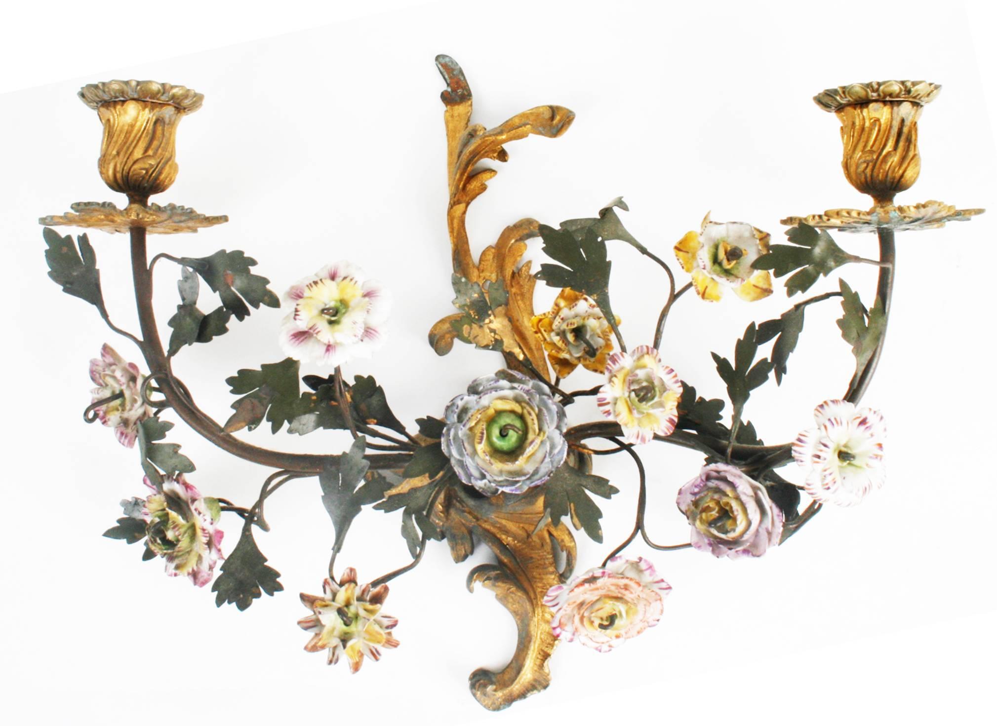 A pretty pair of French tôle and gilt bronze sconces with two branches of hand-painted faience porcelain flowers with tôle metal leaves. The two branches have gilt bronze candleholders and bobeches and are supported on an a gilt bronze leaf bracket.