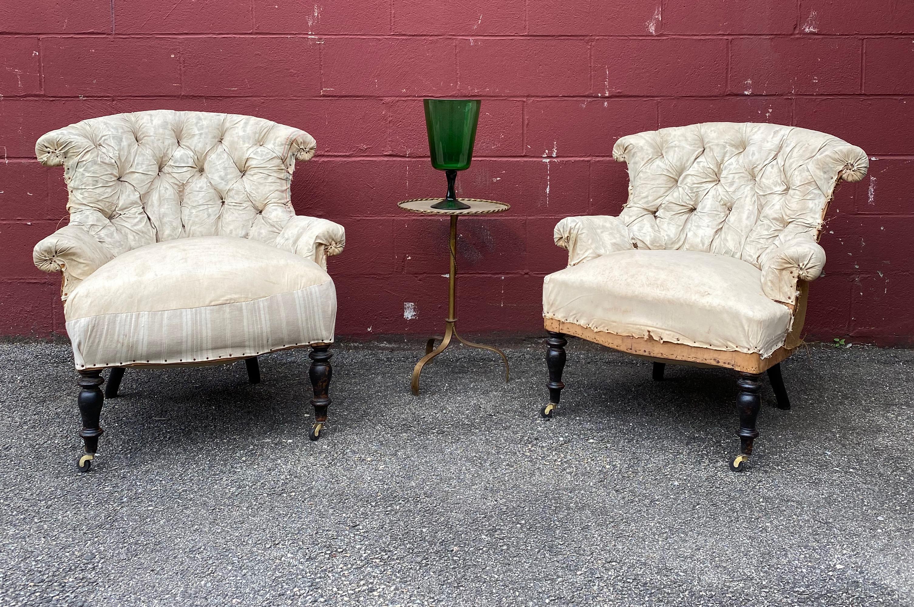 Pair of French Napoleon III  armchairs that have been stripped down to the original muslin. The backs are heavily tufted and have an elegant scroll that carries through to the arms. New casters have been placed on the front legs to create a