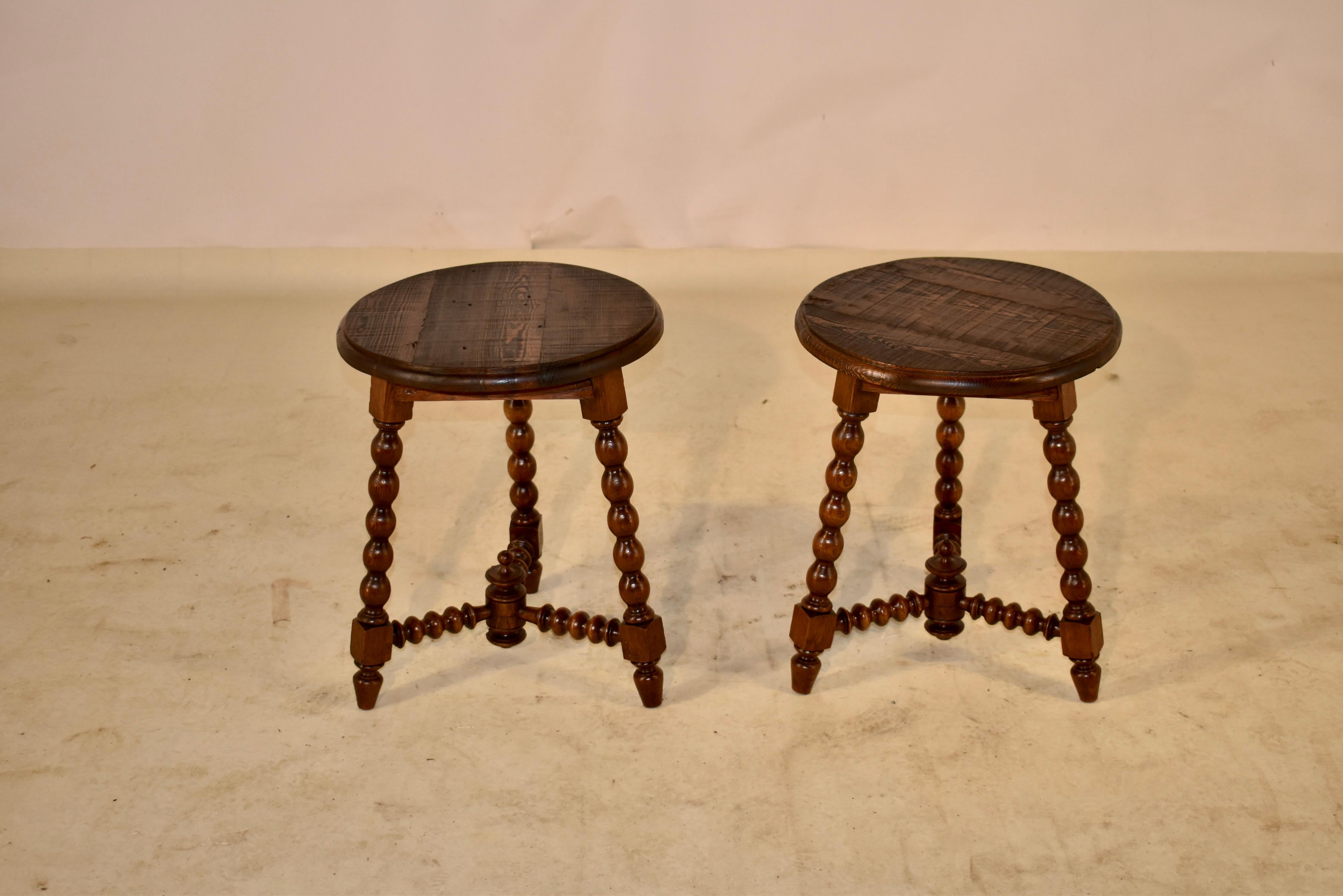 Pair of 19th century French oak stools with pitch pine seats. The seats have routed edges and are resting upon oak bases with simple aprons and splayed, hand turned legs in a bobbin pattern. The legs are joined by complementing hand turned
