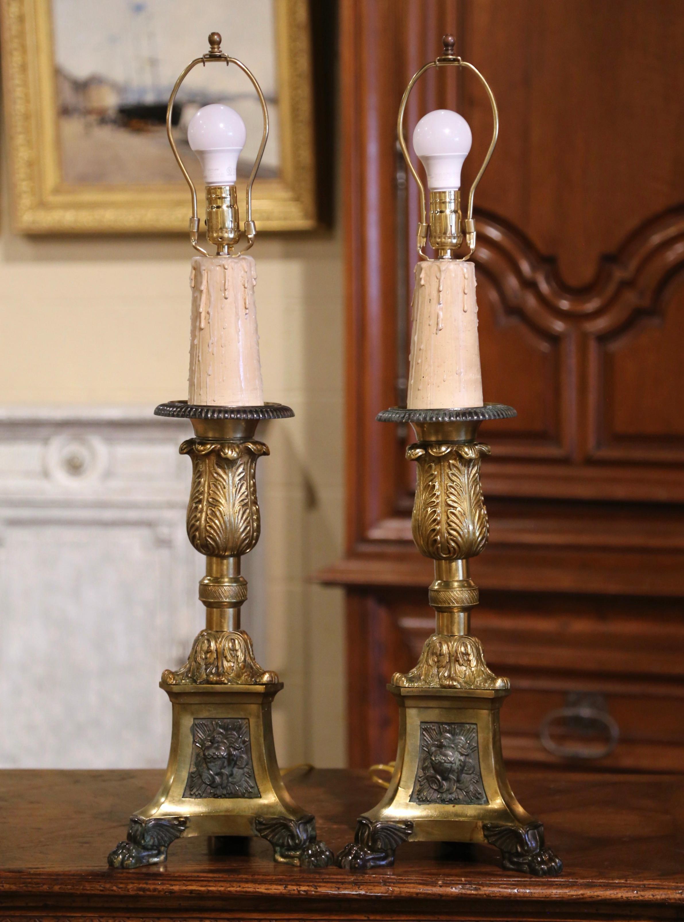 Decorate a living or dining room with these antique church prickets table lamps. Crafted in France, circa 1870, the ornate brass candlesticks sit on a triangle base ending with three paw feet at the base. Each religious candle holder features a