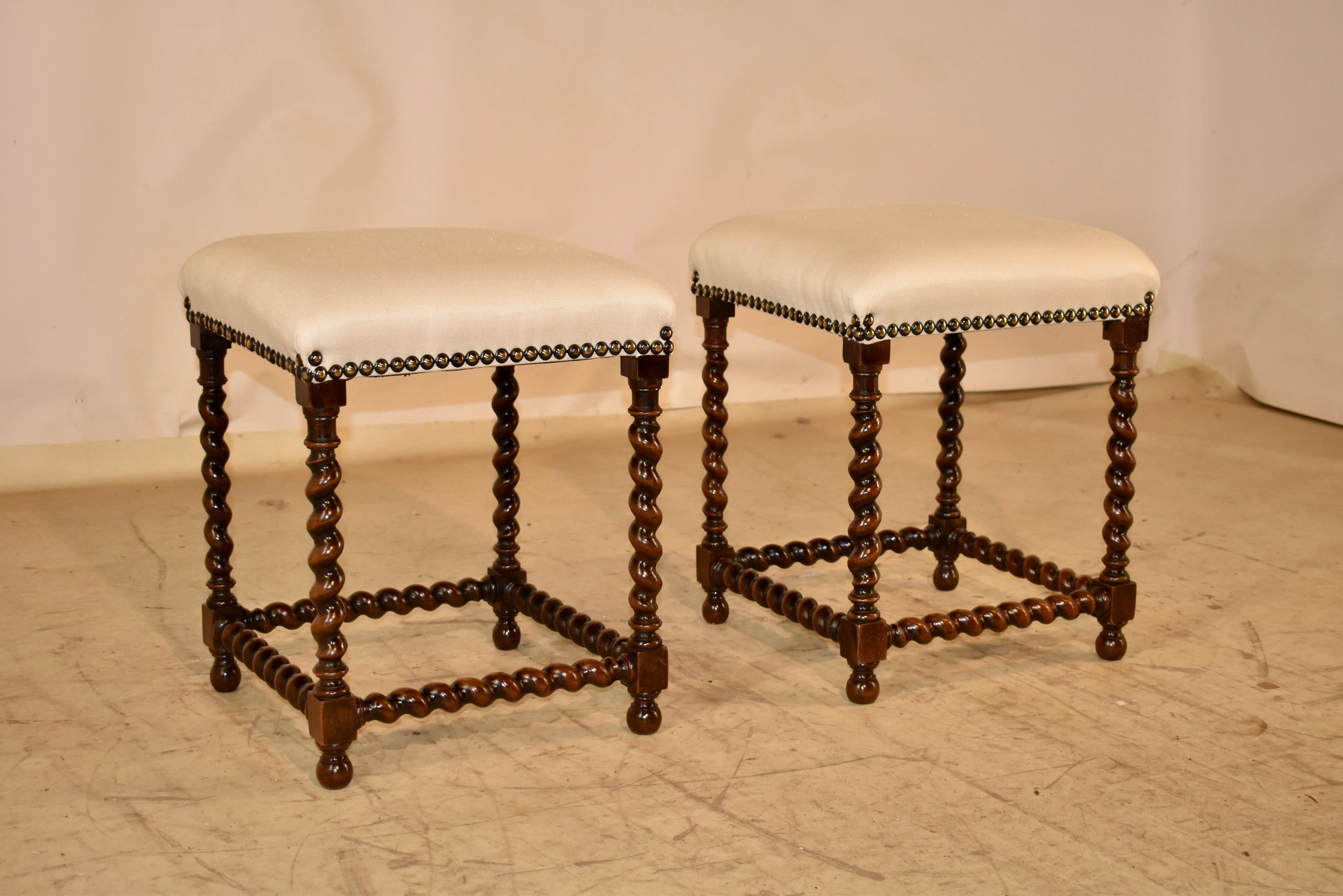 Pair of 19th century oak stools from France with newly upholstered tops.  

The seats are newly upholstered in linen and have nail head trim decoration.  The frames of the stools are made from oak and are supported on hand turned barley twist legs,