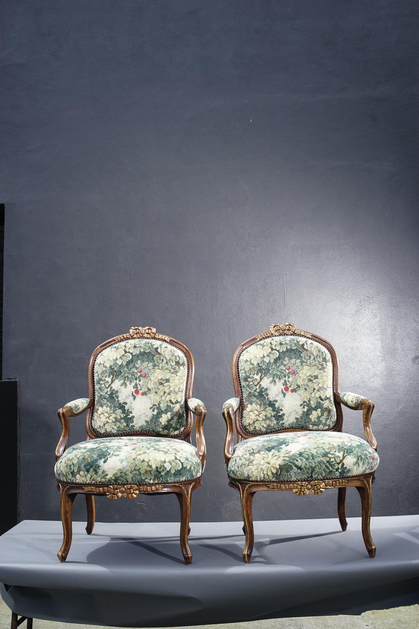 Pair of 19th century French walnut armchairs with carved bow motif. Newly upholstered in old world weavers fabric.