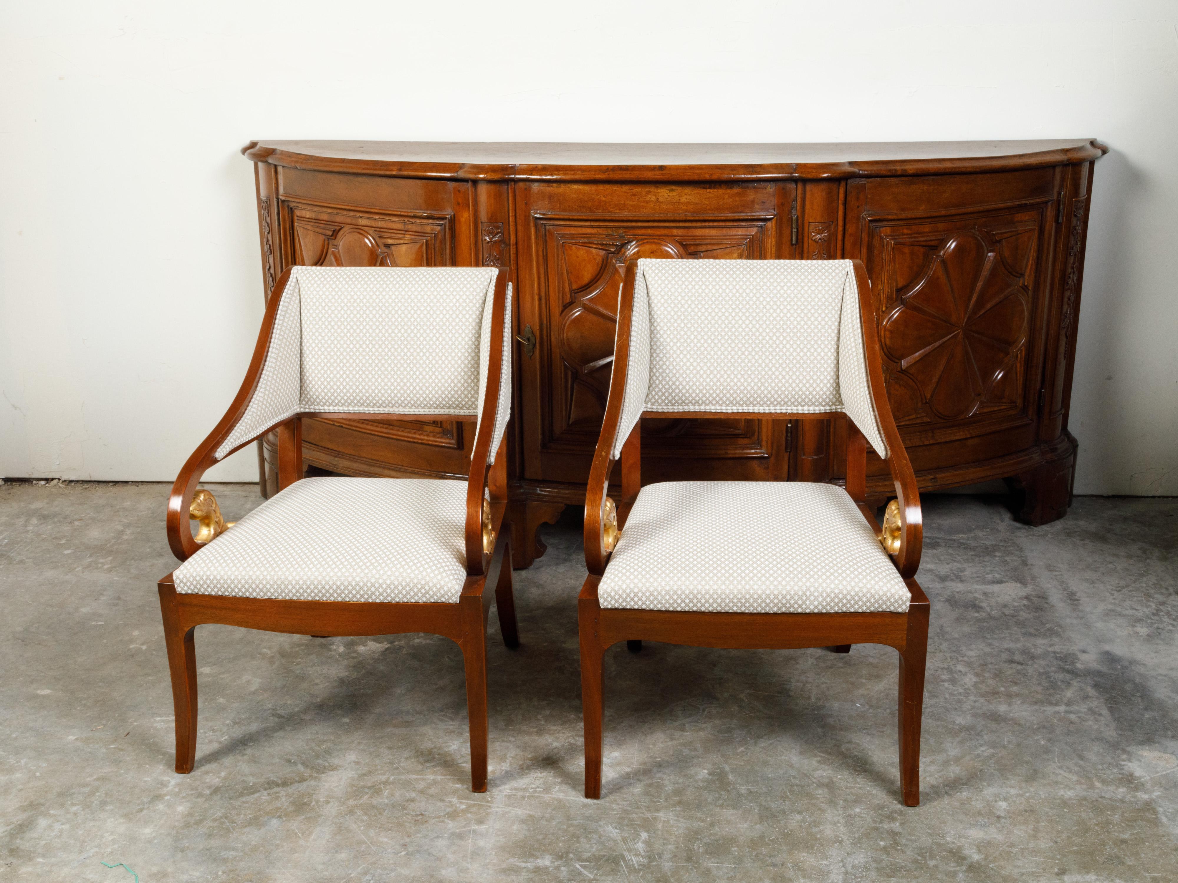 A pair of French walnut armchairs from the 19th century, with giltwood mythical animal carvings and quatrefoil upholstery. Created in France during the 19th century, each of this pair of walnut armchairs features an out-scrolling back connected to