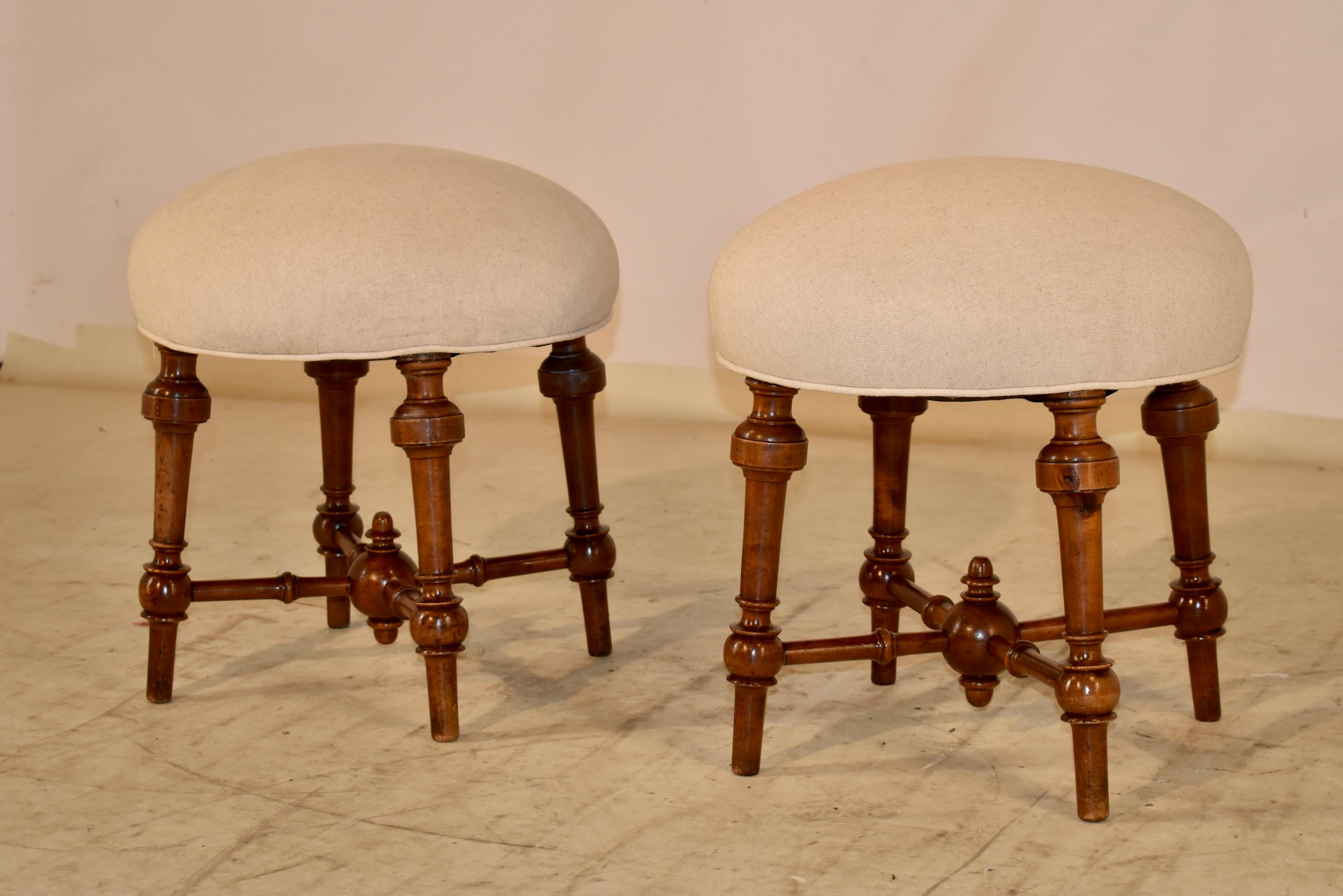 Pair of 19th century walnut stools from France. The seats have been newly upholstered in linen and finished with single welt decoration. The seats are round and are sitting on top of a solid walnut frame with splayed and hand turned walnut legs. The