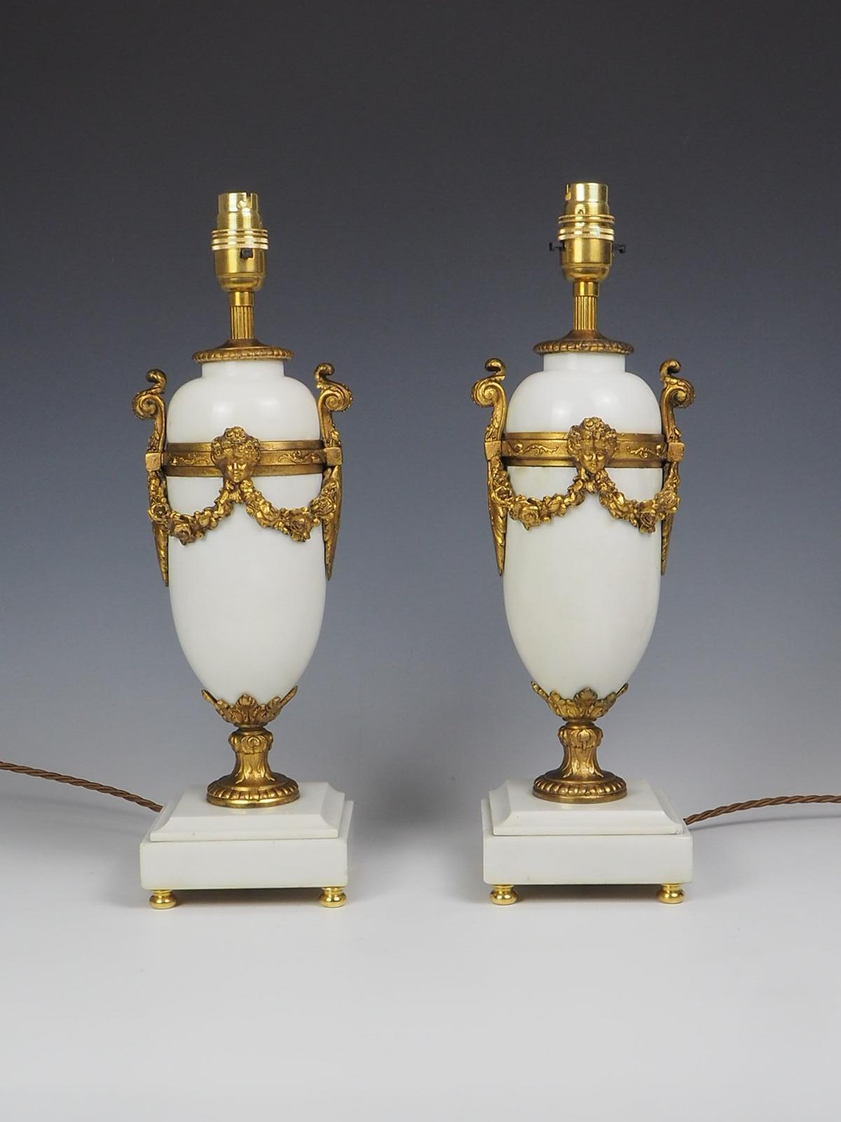 Ein exquisites Paar französischer Tischlampen aus weißem Marmor und Vergoldung aus dem 19. Jahrhundert strahlt Eleganz und Raffinesse aus. Der quadratische weiße Marmorsockel mit flacher Rückseite bietet eine stabile Basis für die Mantelregallampen