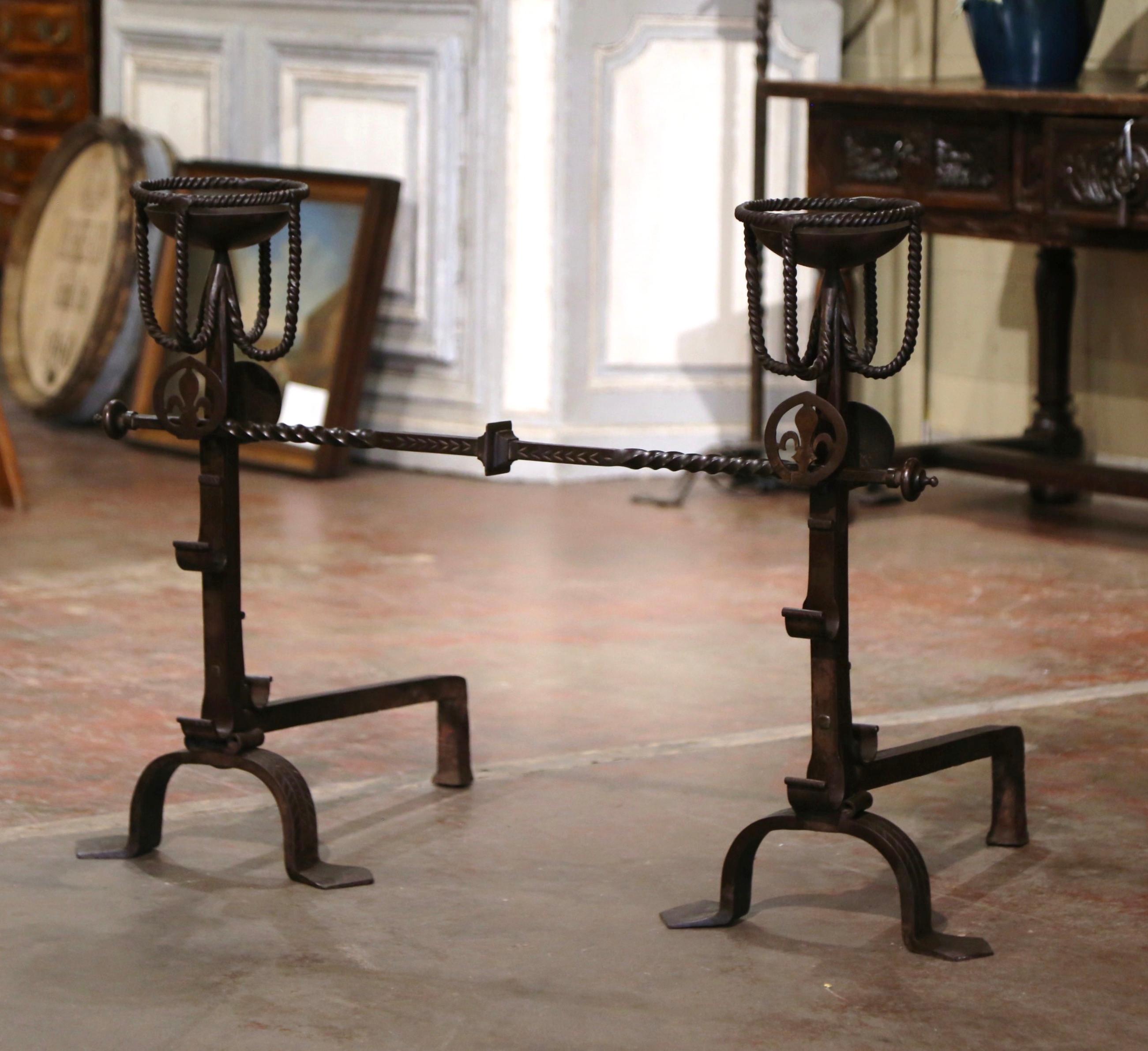 Decorate a fireplace with this elegant pair of antique wrought iron andirons with matching cross bar. Forged in France, circa 1820, and standing on three feet, the andirons called “Landiers” in French, feature a rounded shape cupped top; they were