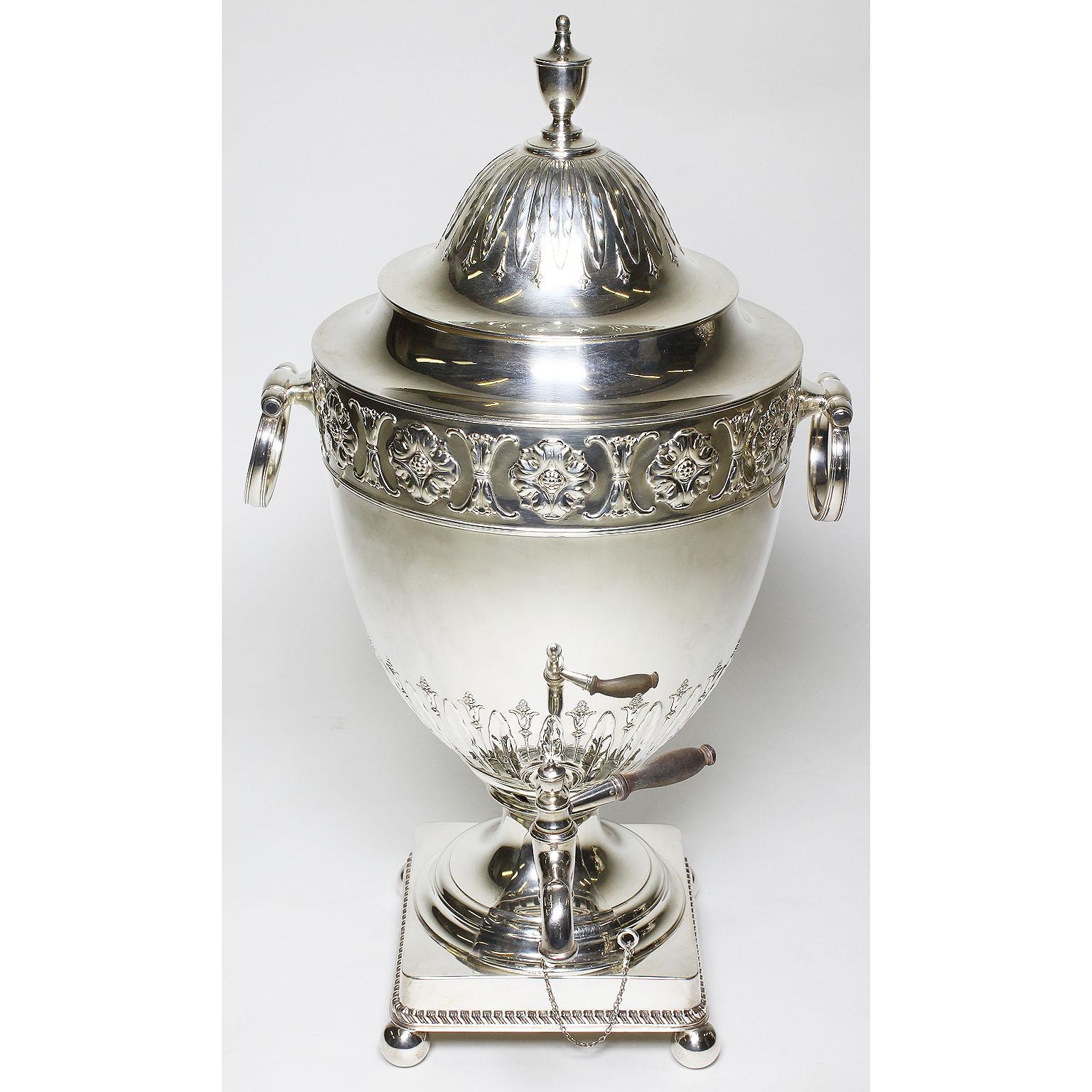 A fine and large pair of English 19th century George III style plated hot water-tea Samovars, each urn-form finely chased with a floral design reservoir with side ring-shaped handles, surmounted by a domed cover and raised on square base and ball