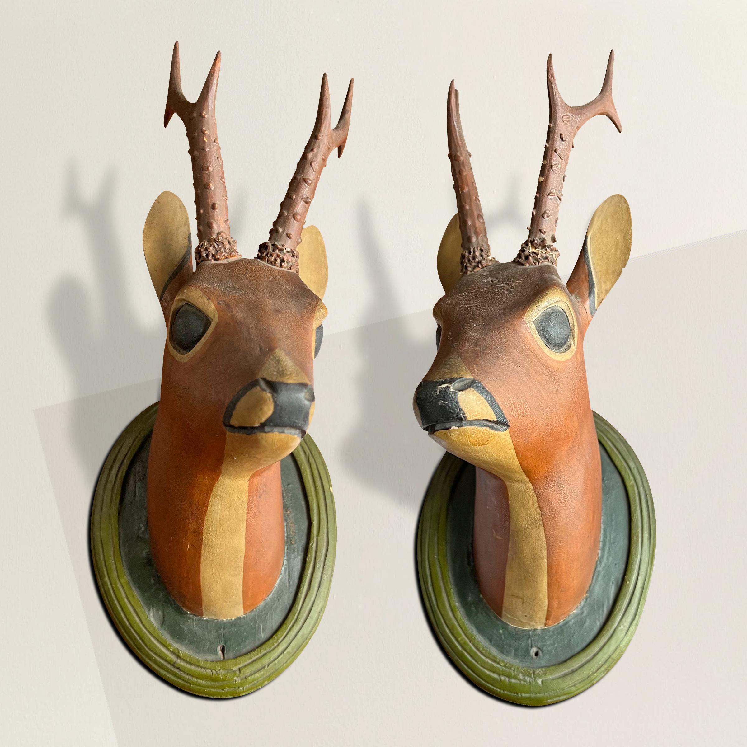 A charming and whimsical pair of 19th century German folk art carved wood roe deer mounts with expressive hand-painted faces and carved and painted wood antlers, mounted on oval wall plaques. The perfect decoration in your kids' room, or for the