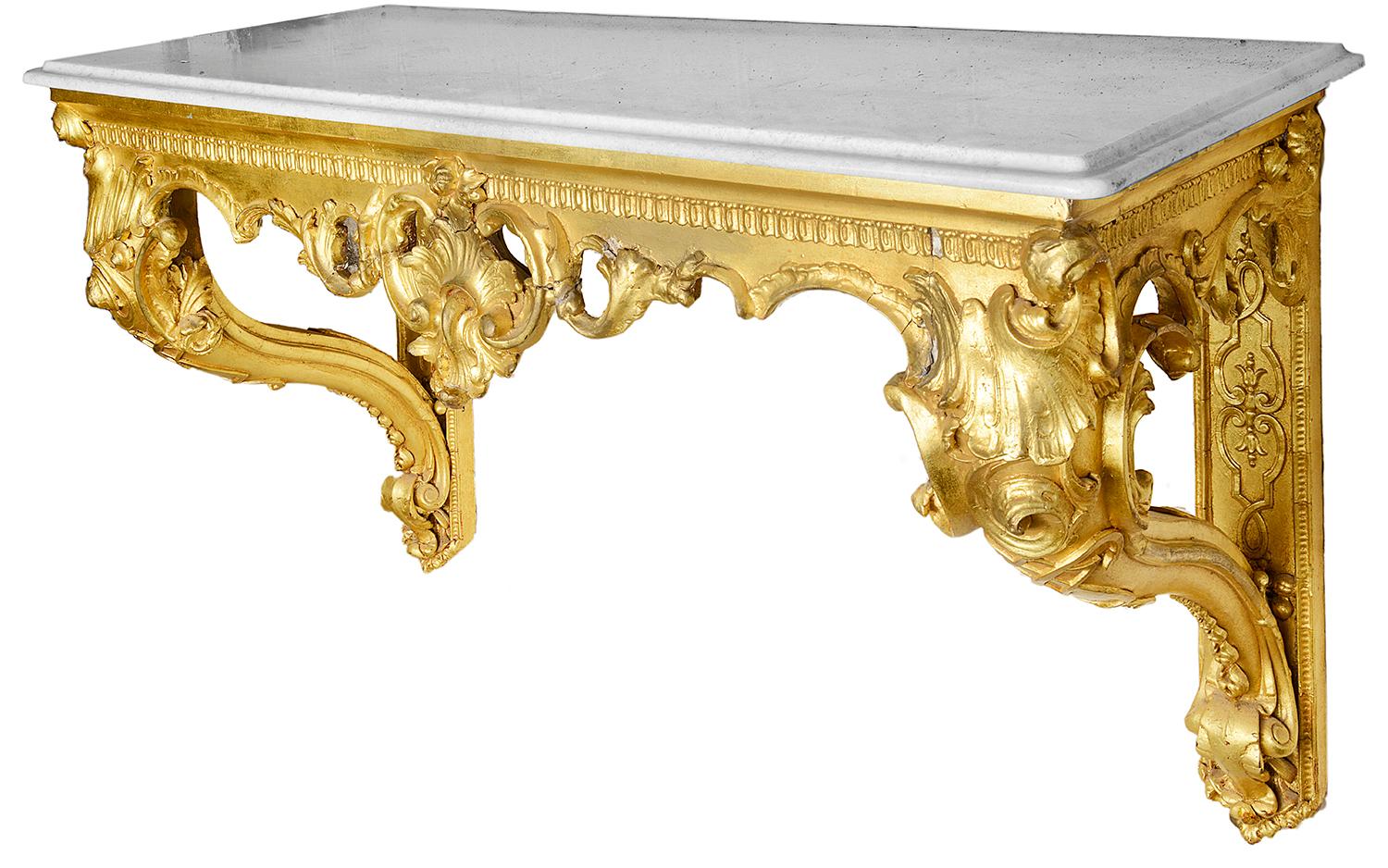 A pair of 19th century gilded wood and gesso console tables, each with their original white marble tops, scrolling cabriole supports to either end and classical C scroll and foliate decoration to the frieze.