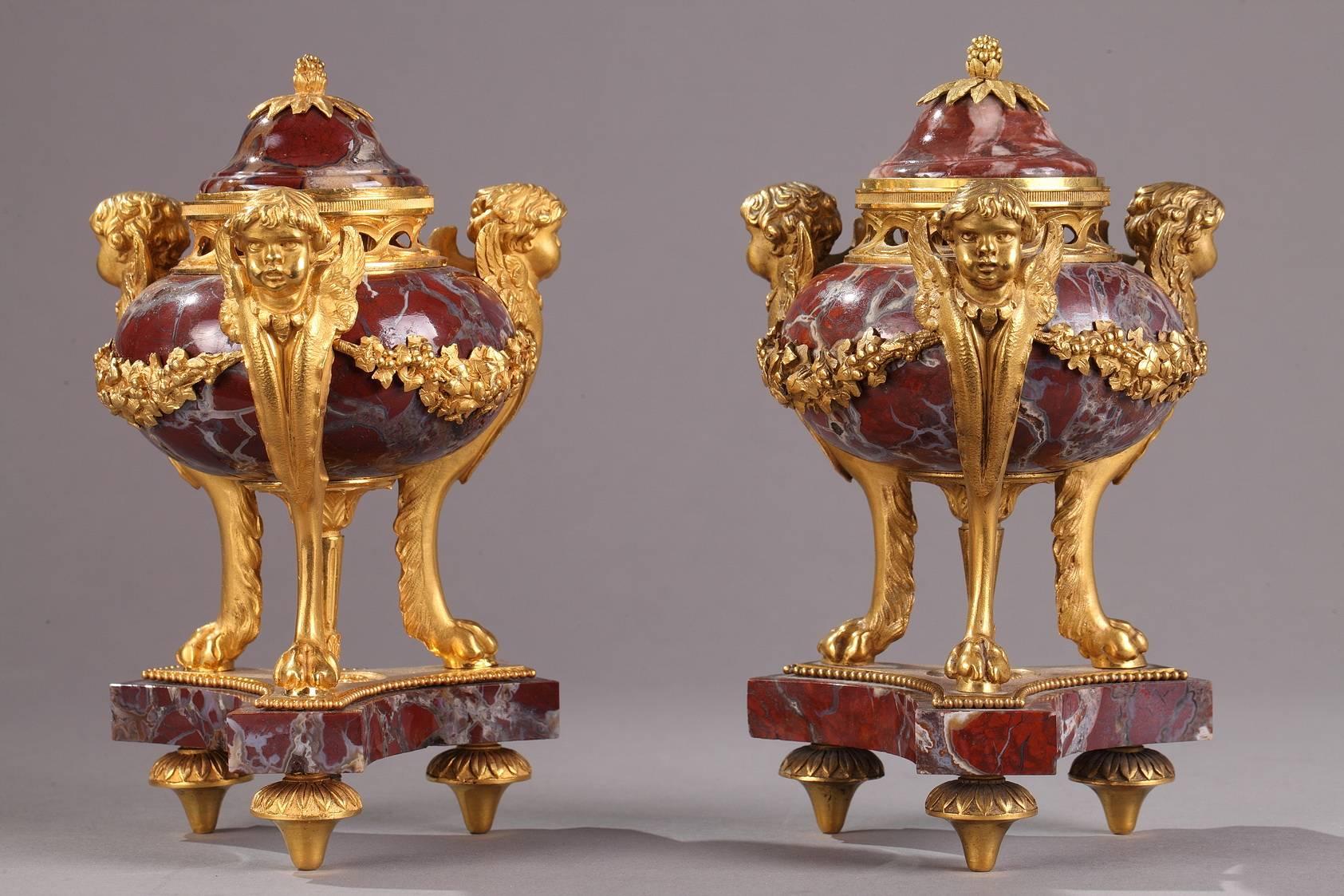 Pair of small, gourd-shaped incense burners in purple, Breche marble and gilt bronze. The bodies of the burners are decorated with alternating garlands and winged cupid heads. Each of the cupid's bodies tapers down to terminate in a clawed lion's