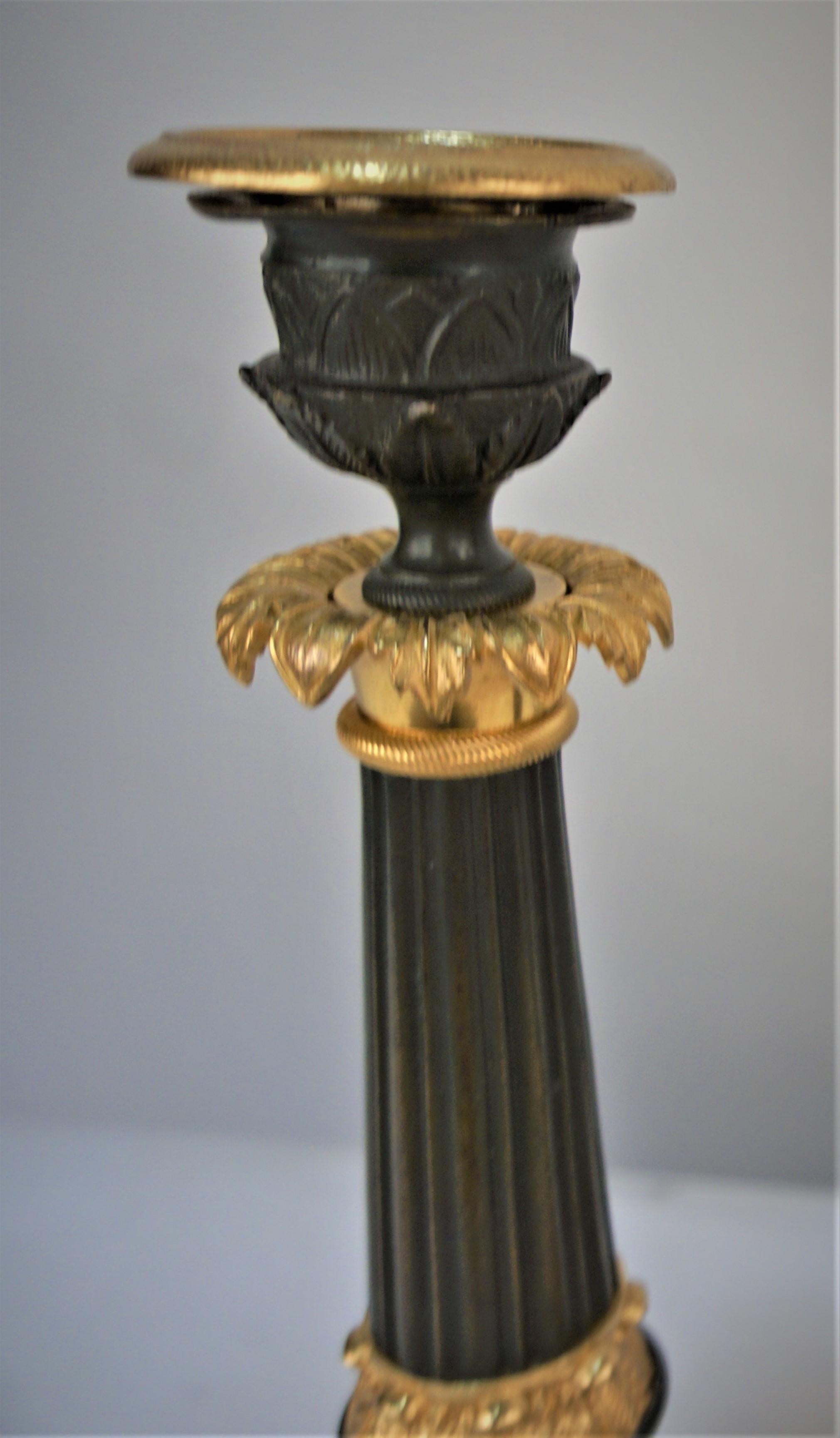 A pair of 19th century Regency gilt bronze and black candlesticks, with three lion's claws.