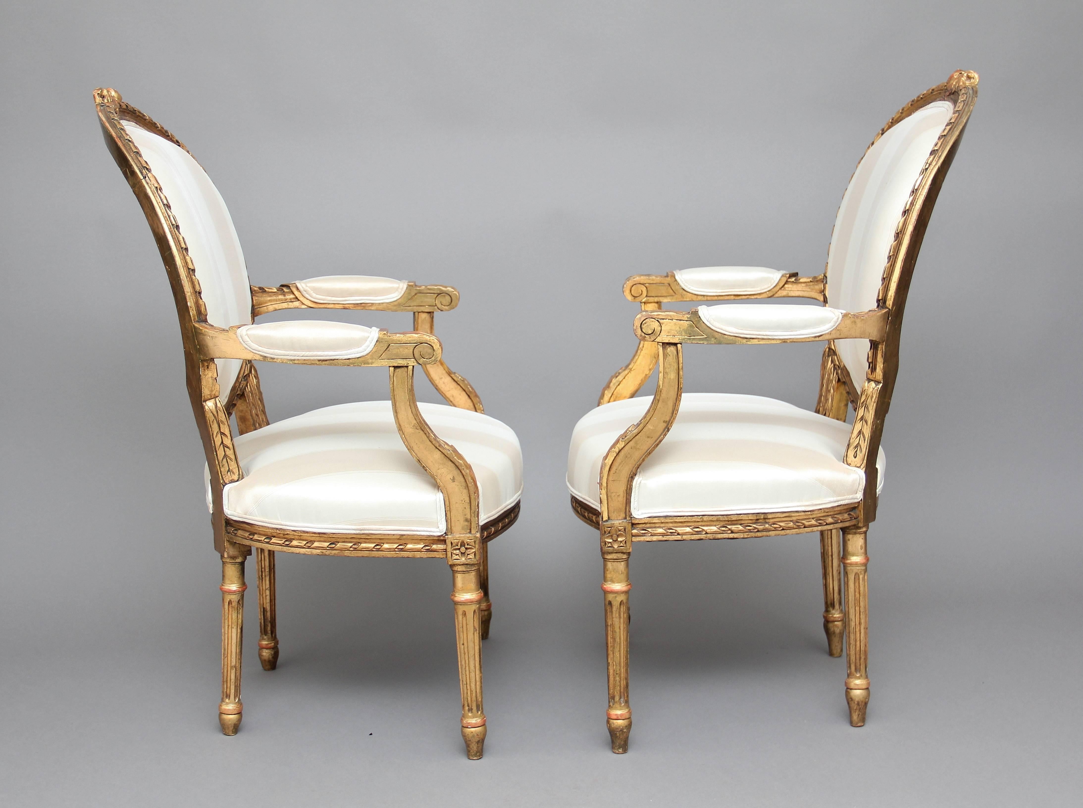 A nice pair of 19th century French giltwood and carved open armchairs, the oval padded backs with a carved frame and carved decoration at the top, padded arms with swept uprights decorated with acanthus leaf, the cream upholstered seat having a