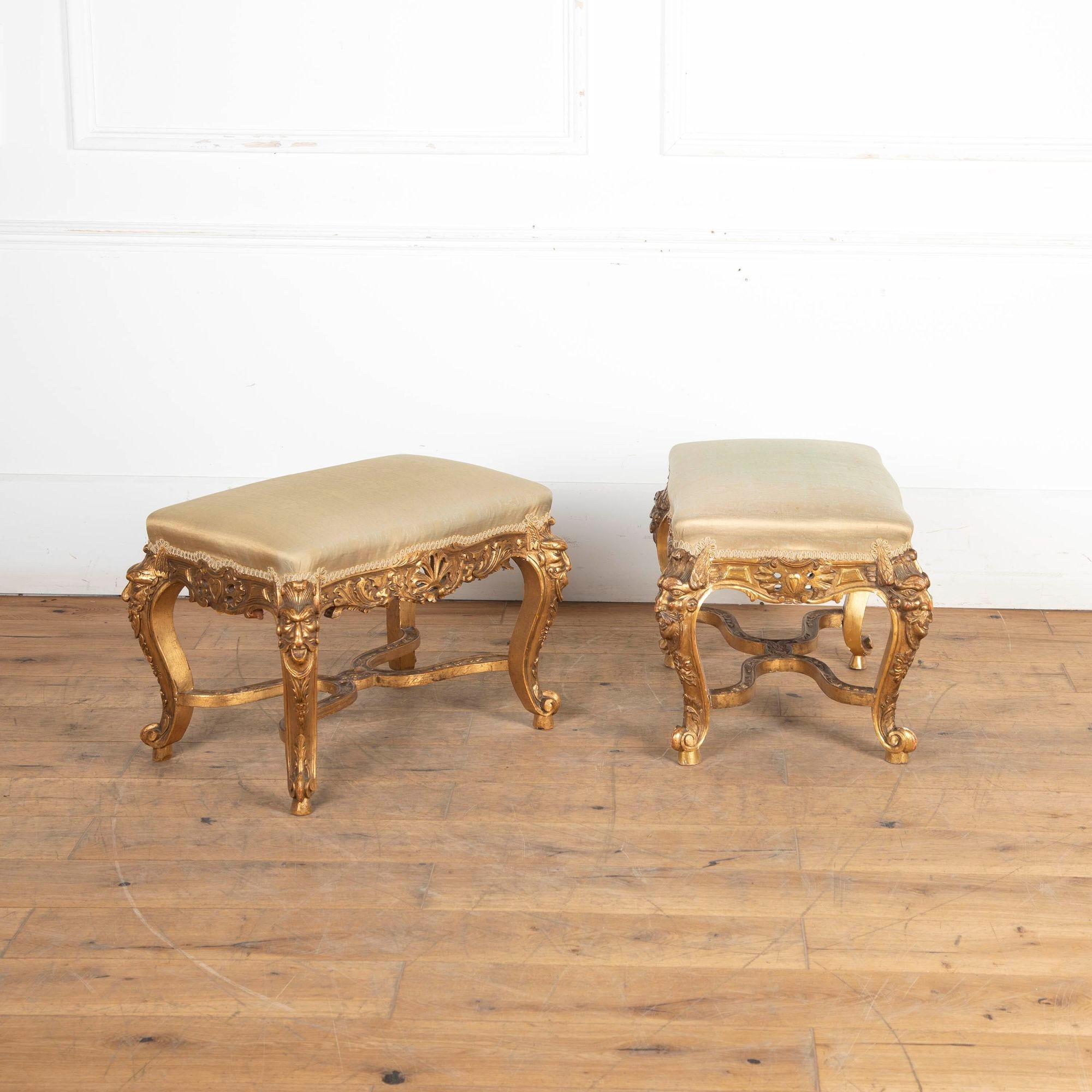 Highly decorative pair of 19th century carved giltwood stools with upholstered seats covered in antique water-patterned pale green silk.
The ornately carved aprons with trailing foliage on either side of pierced cartouches and flanked by cabriole