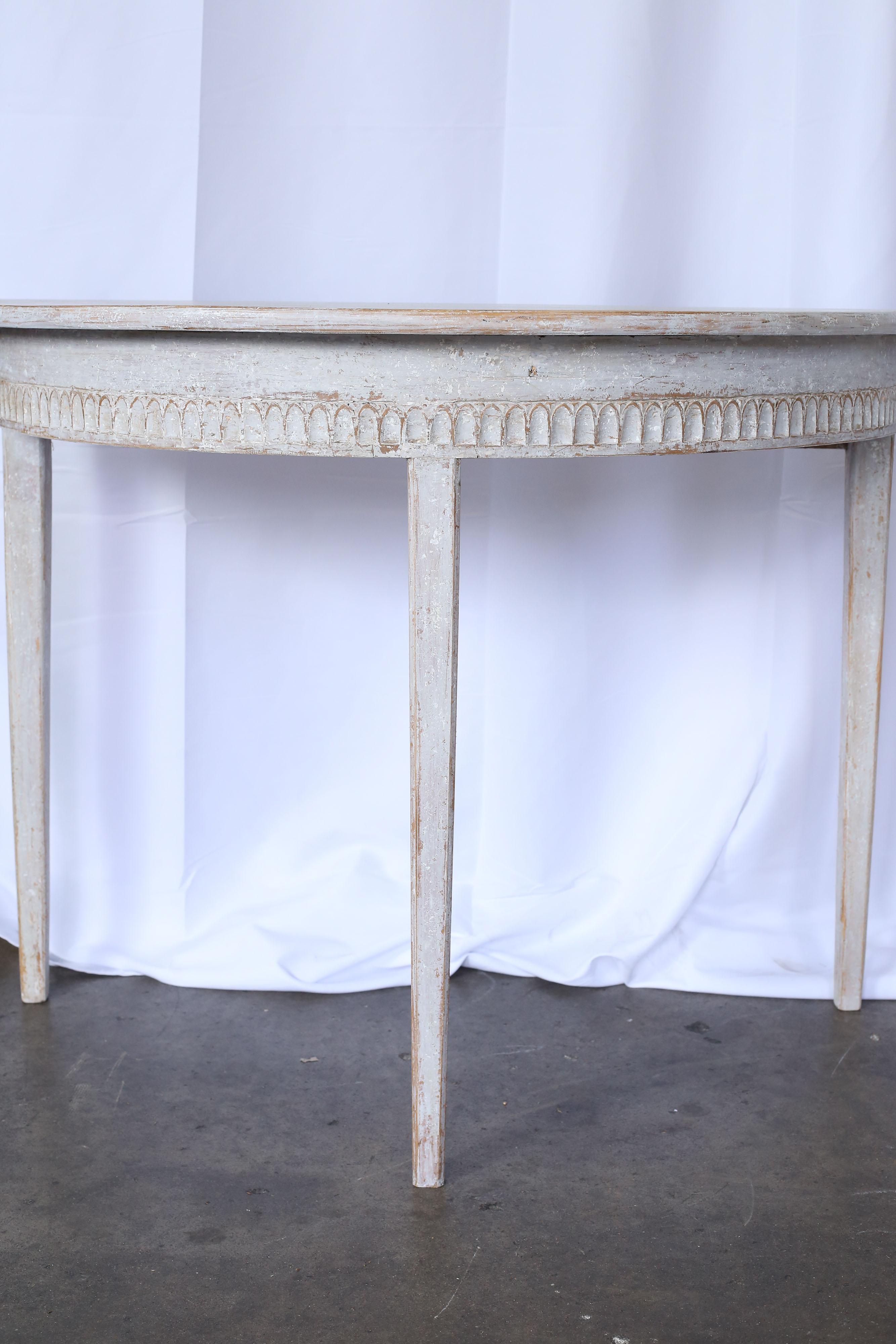 Pair of 19th century Gustavian demilune tables with original paint. A carved detail is visible around the perimeter.