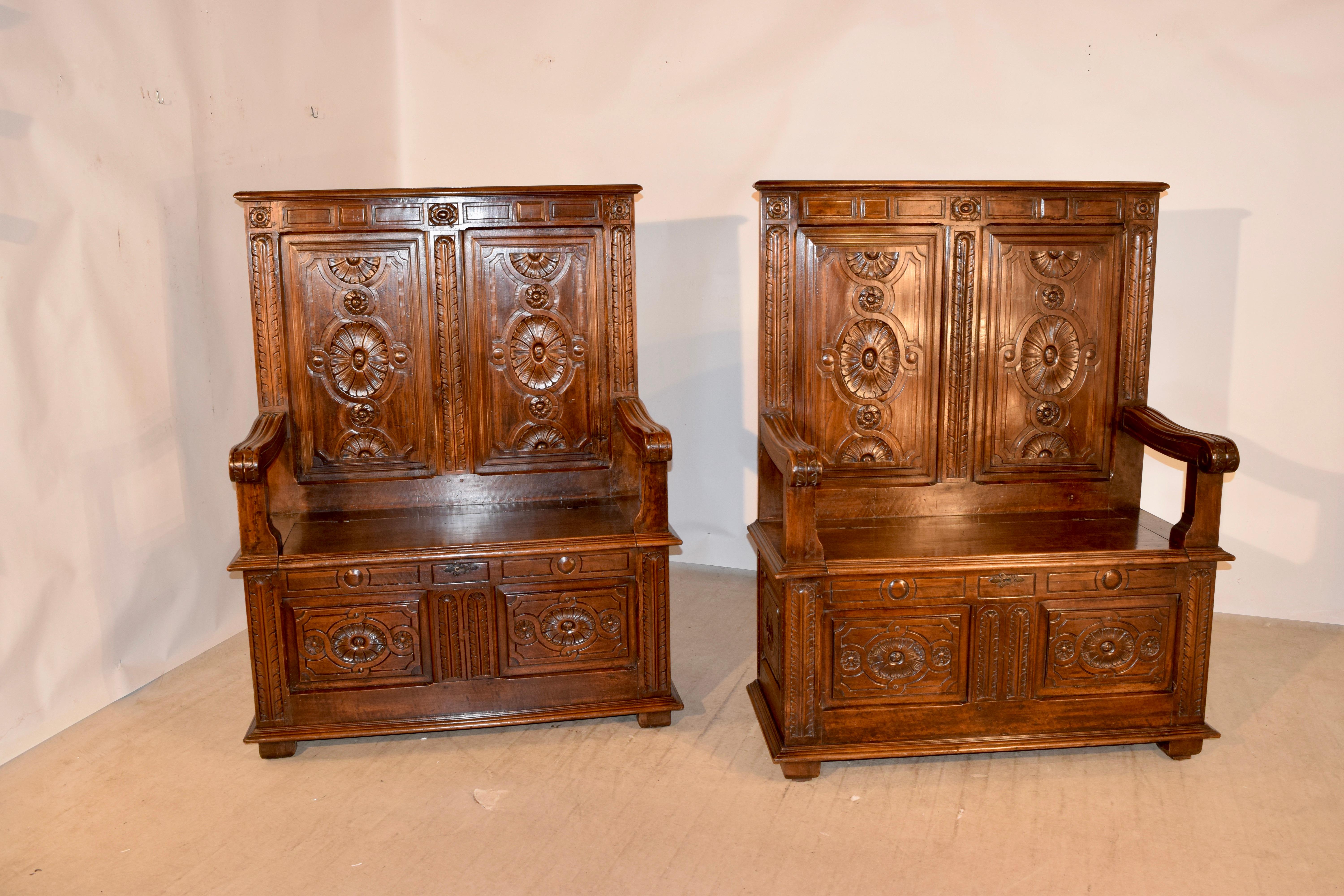 Pair of 19th century oak hall benches from England with lovely hand paneled backs which are hand carved decorated as well. The seats lift to reveal storage compartments. The base of the benches have hand carved raised panels on three sides, and are