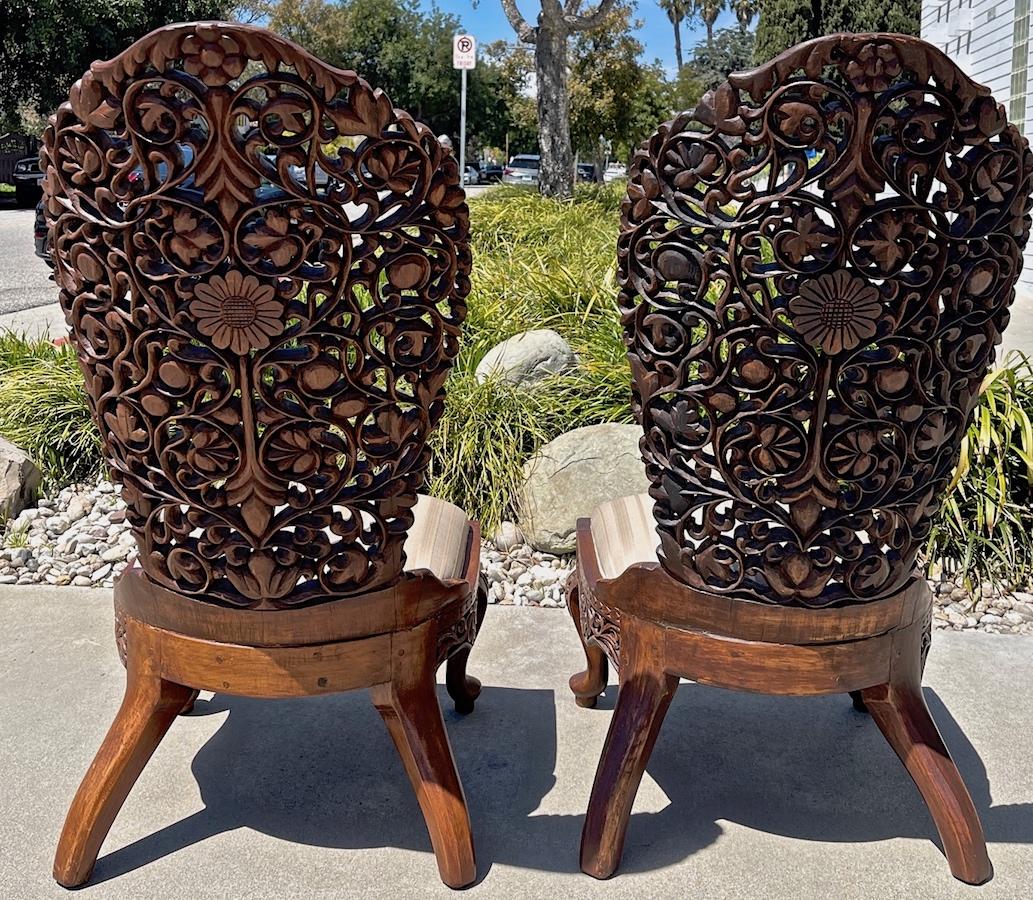 This is a pair of 19th century nursing chairs from Myanmar in excellent condition. The seats are covered in the original silk. The motif of the hand carving is of flowers and branches. These chairs are very low so they would be used more for