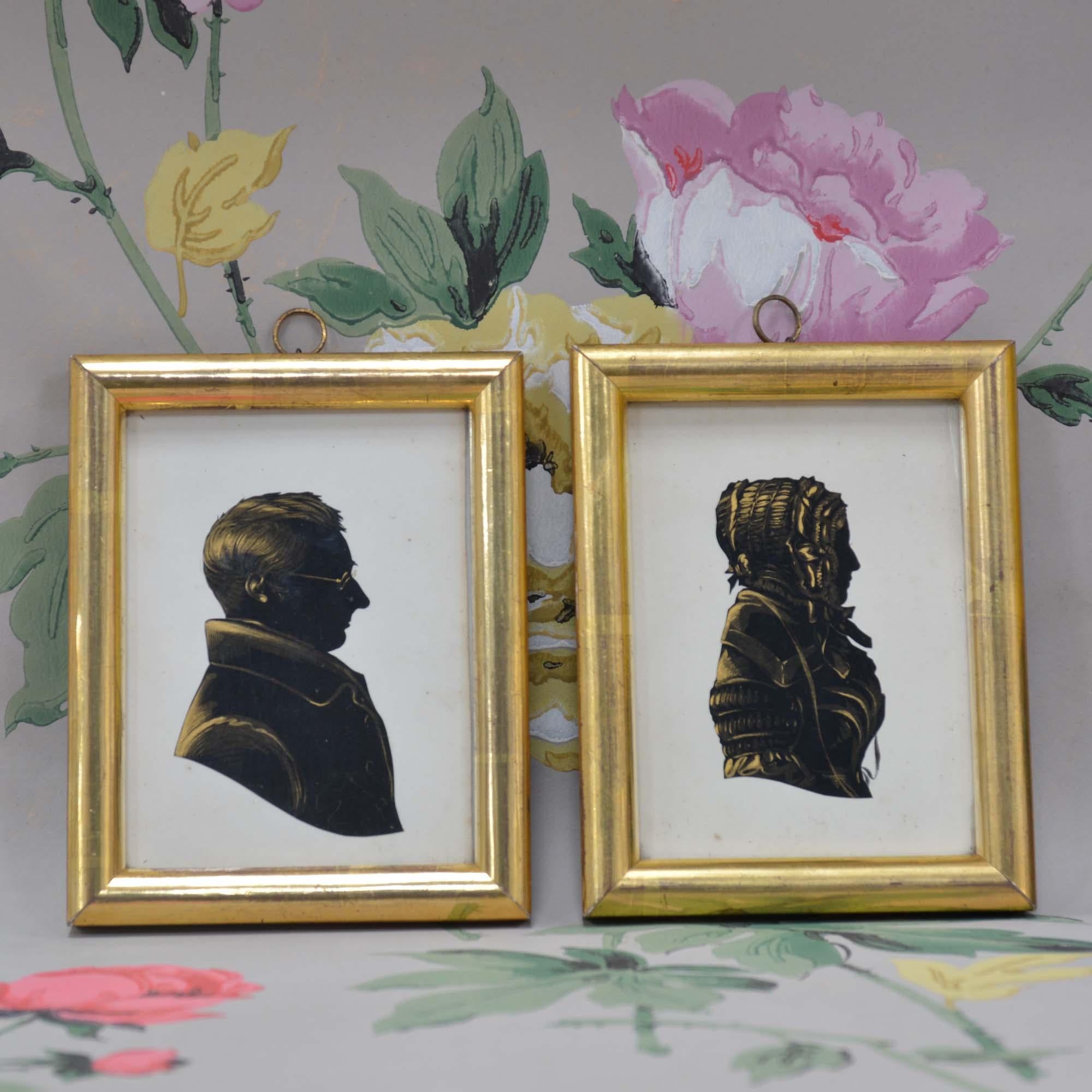 A pair of silhouettes, head and shoulders of a man in coat ask wearing glasses and a woman in a dress and bonnet, hand cut in black paper, heightened in gold.  Framed in uniform gilt frames.
British, late 19th century 

12.5cm H, 10cm W the