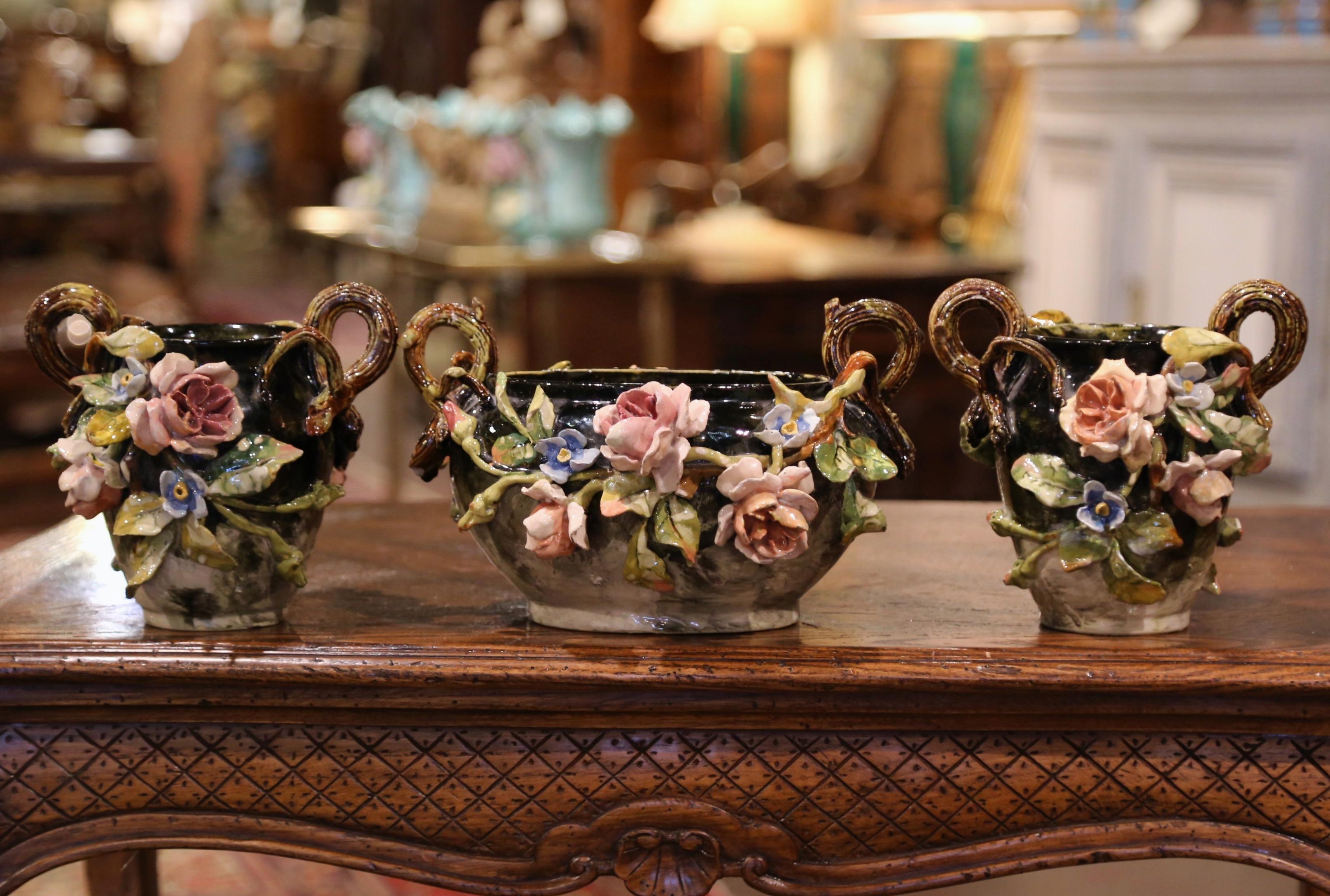 Dieses schöne, farbenfrohe, handbemalte antike Majolika-Set wurde um 1870 in Montigny sur Loing, Frankreich, hergestellt. Jede Keramikvase, einschließlich der passenden Jardiniere, ist mit verschnörkelten Griffen in Form von Zweigen verziert und