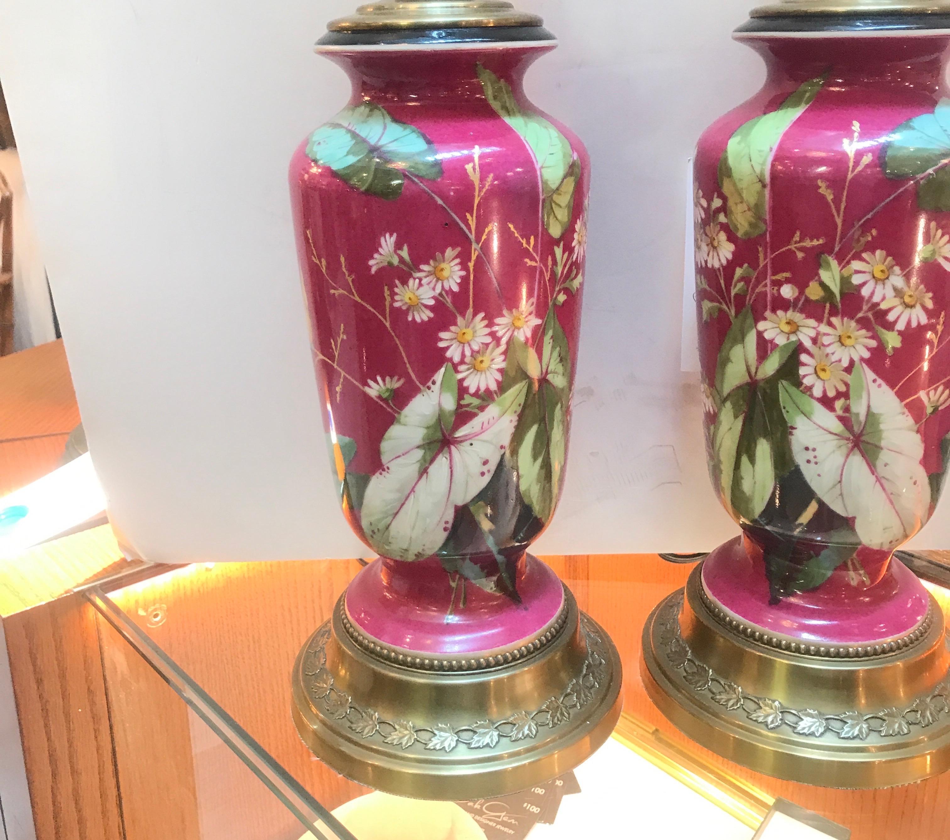 Exquisite pair of mid-19th century hand painted English porcelain vases now as lamps. The vibrant fuchsia vases with floral and leaf decoration and a true original pair being a mirror image of each other. The top with a jade sphere finial. The