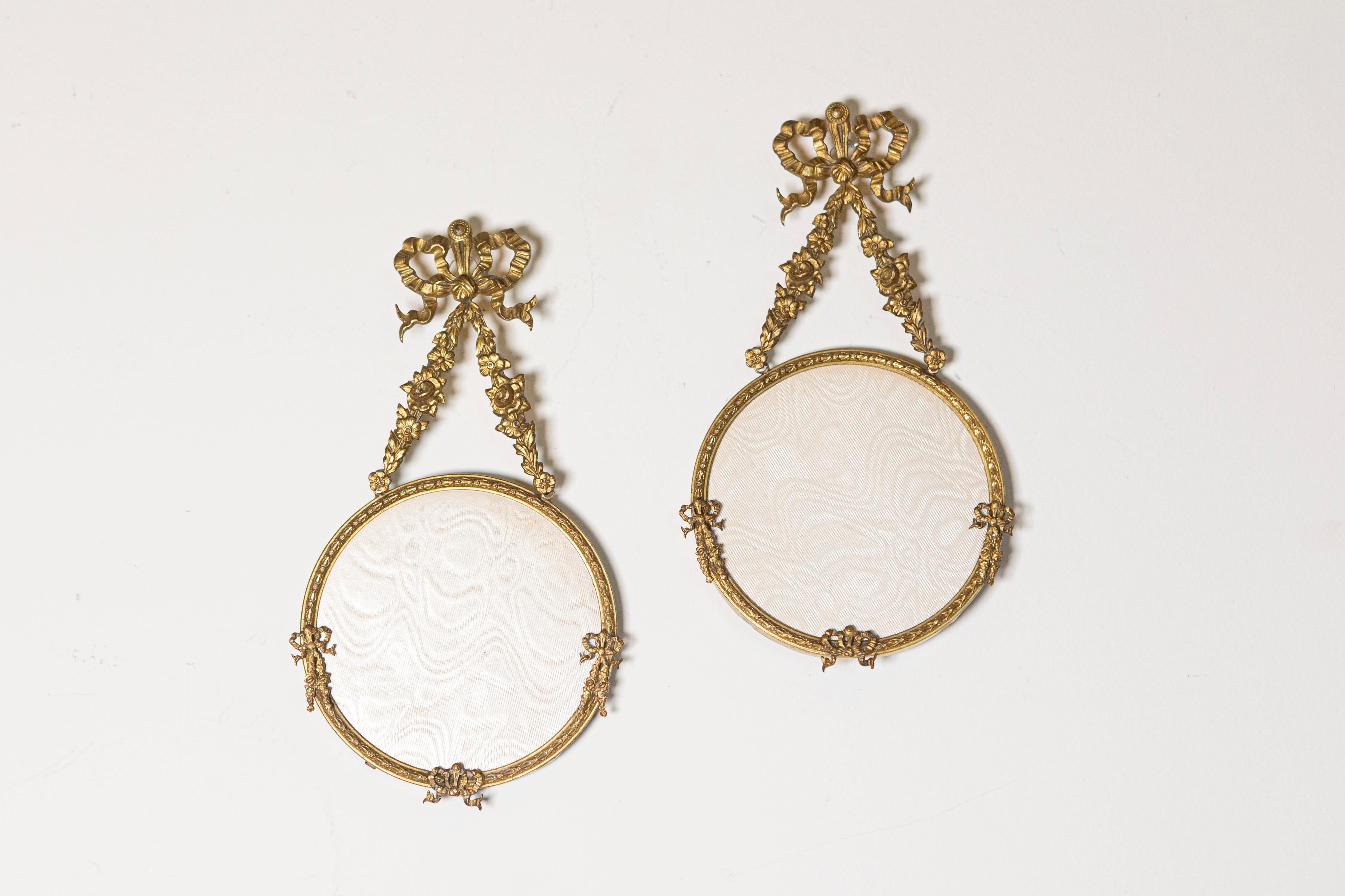 Dieses exquisite Set aus zwei französischen Hängerahmen aus dem 19. Jahrhundert strahlt zeitlose Eleganz und Charme aus. Jeder aus vergoldeter Bronze gefertigte Rahmen ist mit aufwändigen Details wie zarten Blumengirlanden, Schleifenbändern und