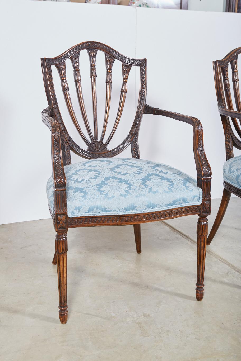 Pair of late 19th century Hepplewhite style armchairs in the French taste. Beautiful mahogany frames incorporating numerous classical motifs including bundled reeds, paterae, guilloche carving on the arms and surrounding the shield back, and fluted