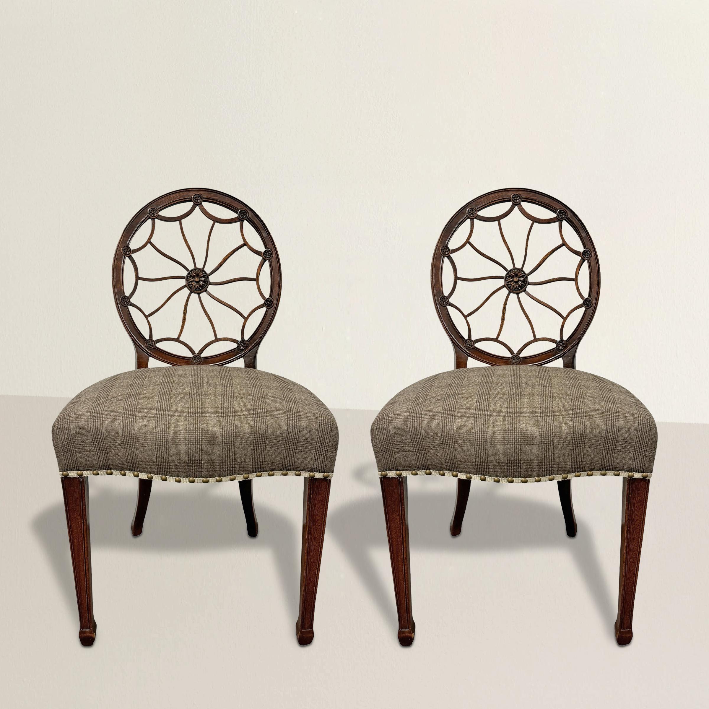 This pair of mid-late 19th-century American Hepplewhite side chairs exemplifies the elegance and refinement of the Hepplewhite style, distinguished by their spiderweb backs featuring delicate floral rosettes at the center. The sleek and graceful