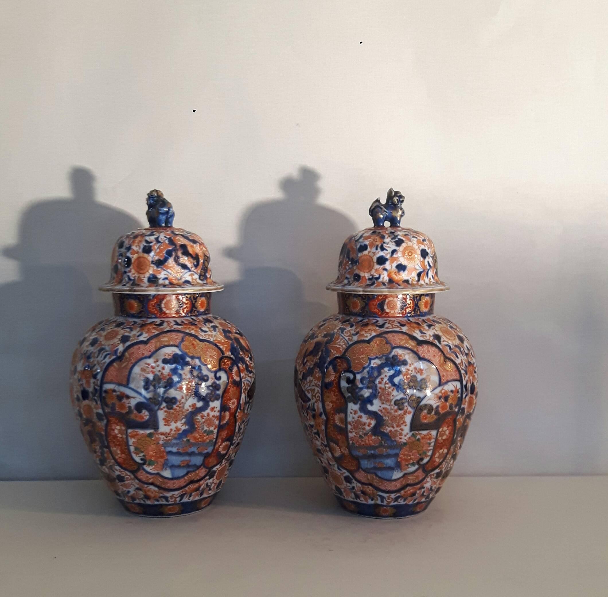 A heavily decorated pair lidded Japanese Imari vases, the design with cartouches of the tree of life and various flora, the lids adorned by a dog of Foe. The vases are signed by Crouncha.