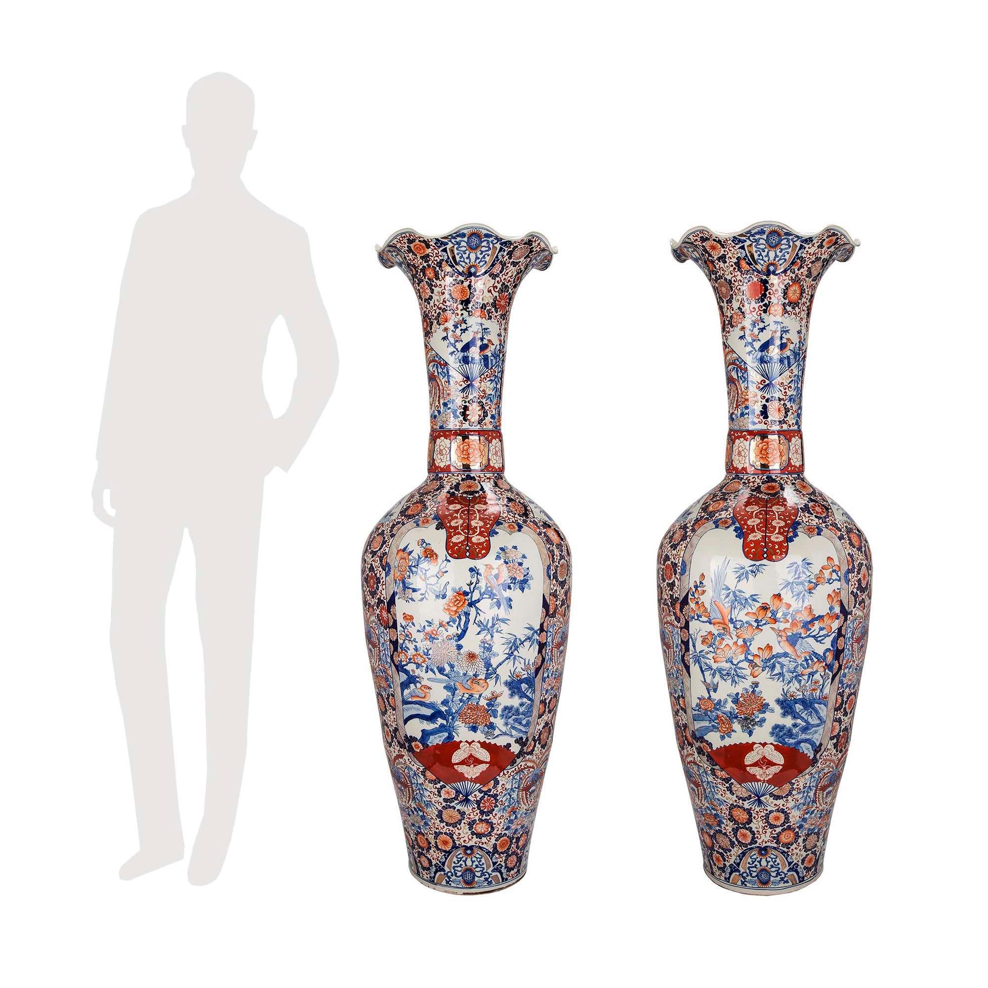 A sensational and very large scale pair of 19th century Imari vases. Each striking vase stands at over 5 feet tall and displays wonderful vivid floral patterns centering charming and detailed floral and foliate scenery. The long impressive necks