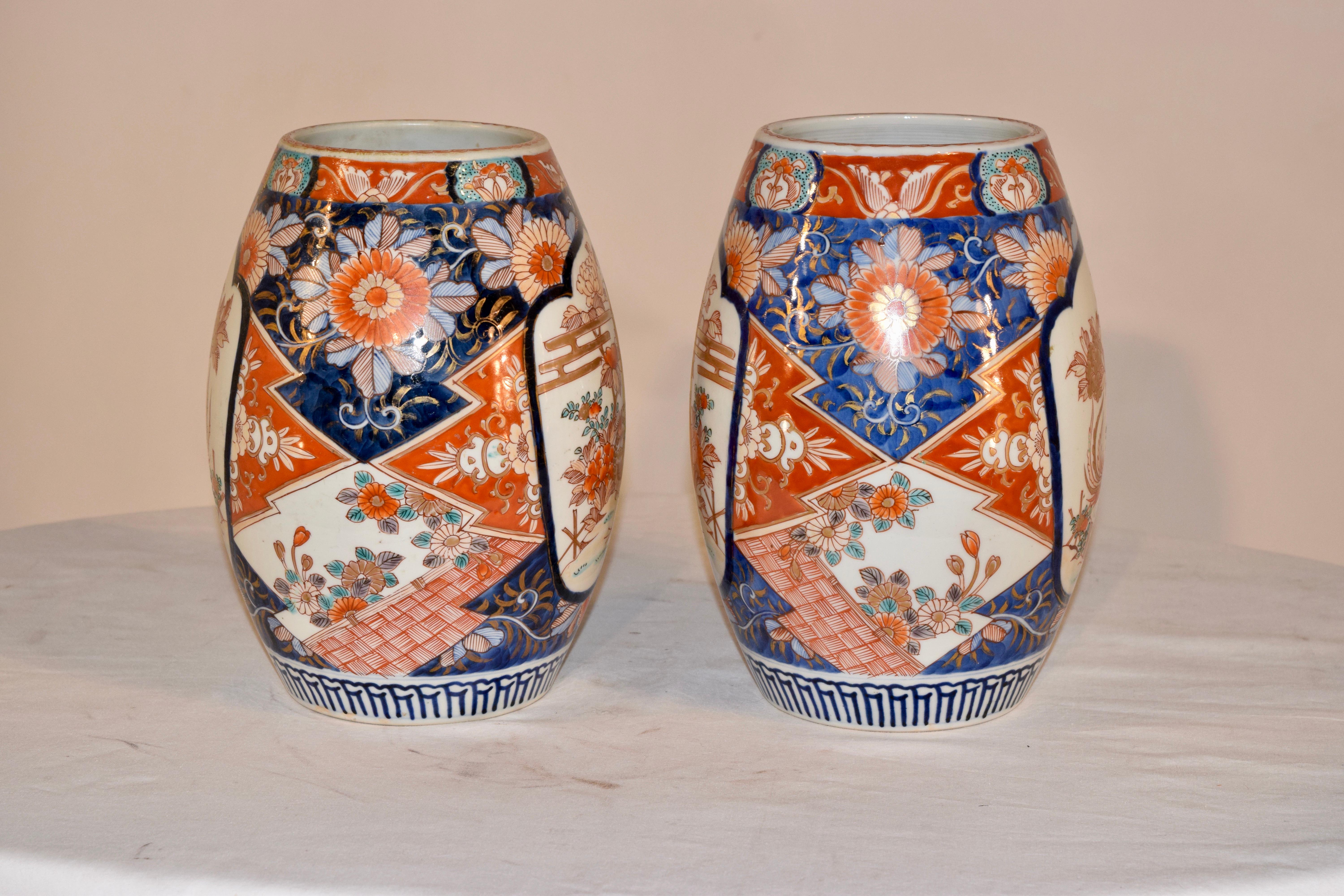 Pair of 19th century Imari vases in an unusual cylindrical shape. Their are two cartouches on each vase depicting a bird in a garden. The cartouches are surrounded by geometric patterns in wonderful colors.