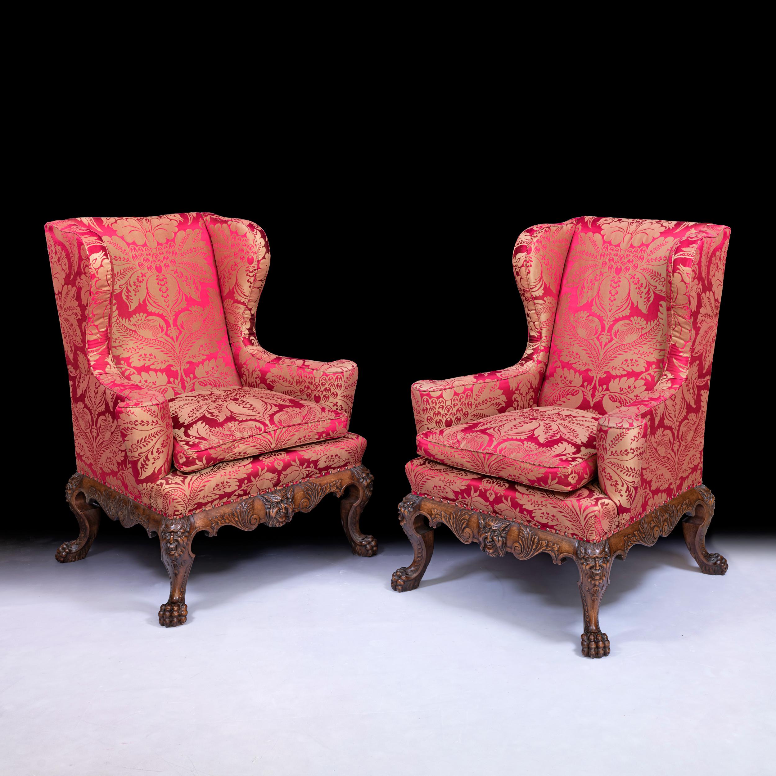 A very fine pair of 19th century Irish George II style wingback chairs upholstered in a silk demask, the substantial cabriole front legs with naturalistic ball and claw feet and beautifully carved with masks to each knee overlapping the deep and