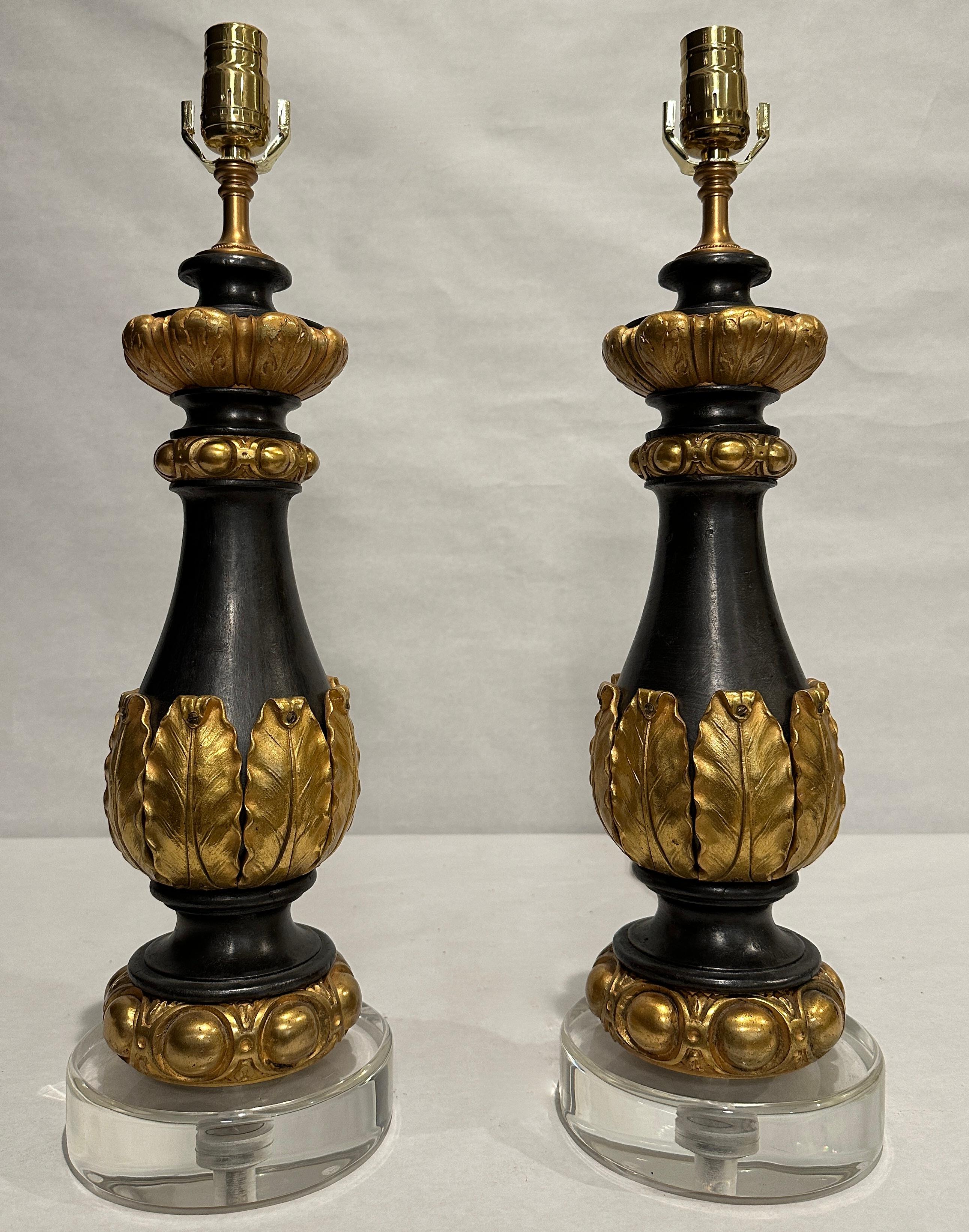 Paar Garnituren aus patiniertem Eisen und vergoldeter Bronze aus dem 19. Jahrhundert als Lampen auf runden Lucitsockeln. Vase aus Korpus umgeben von vergoldeten Bronzeblättern. Ei- und Abnäherform Kragen oben und unten.