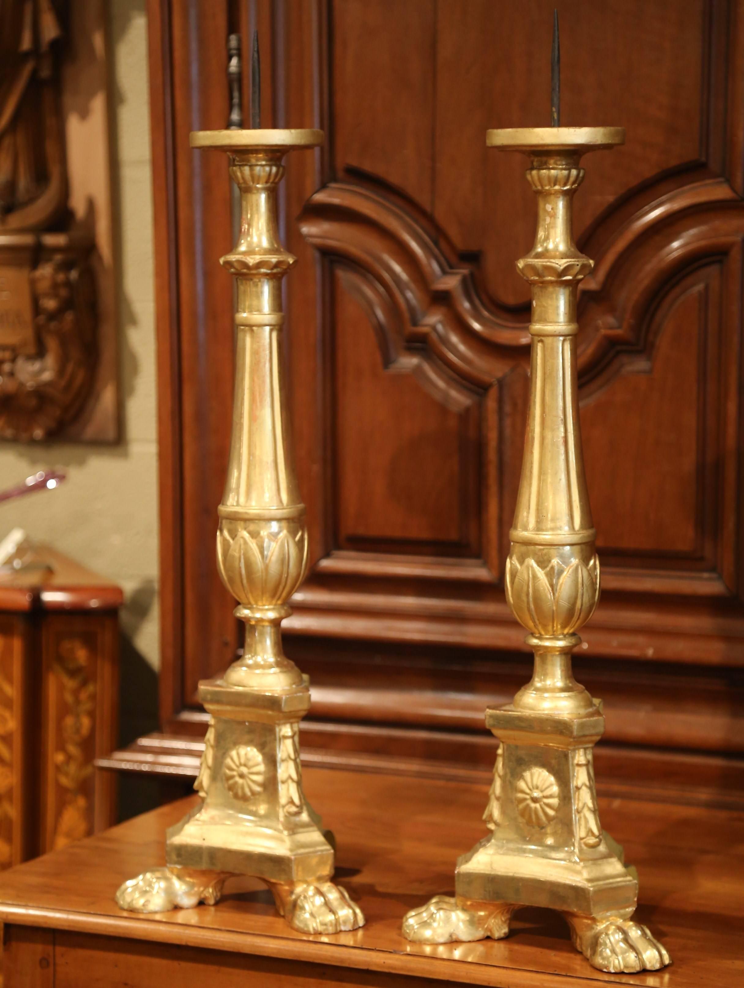 Add an air of drama and elegance to your home with this pair of antique candlesticks from Italy. Carved, circa 1860, each tall pricket has a sturdy triangle base with hand carved acanthus leaves and round flower medallion above small paw feet. The