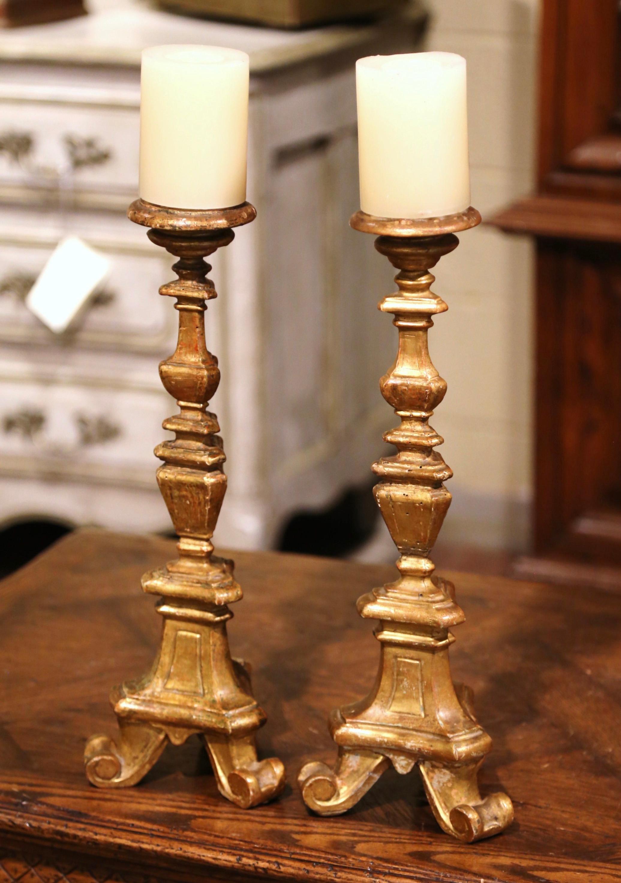 Created in Italy circa 1880, each two-tone candle holder stands on a three-leg base triangle base over a decorative carved stem. The detailed church candlesticks flaunt their beautiful, original patinated gilt finish. Both pieces are in excellent