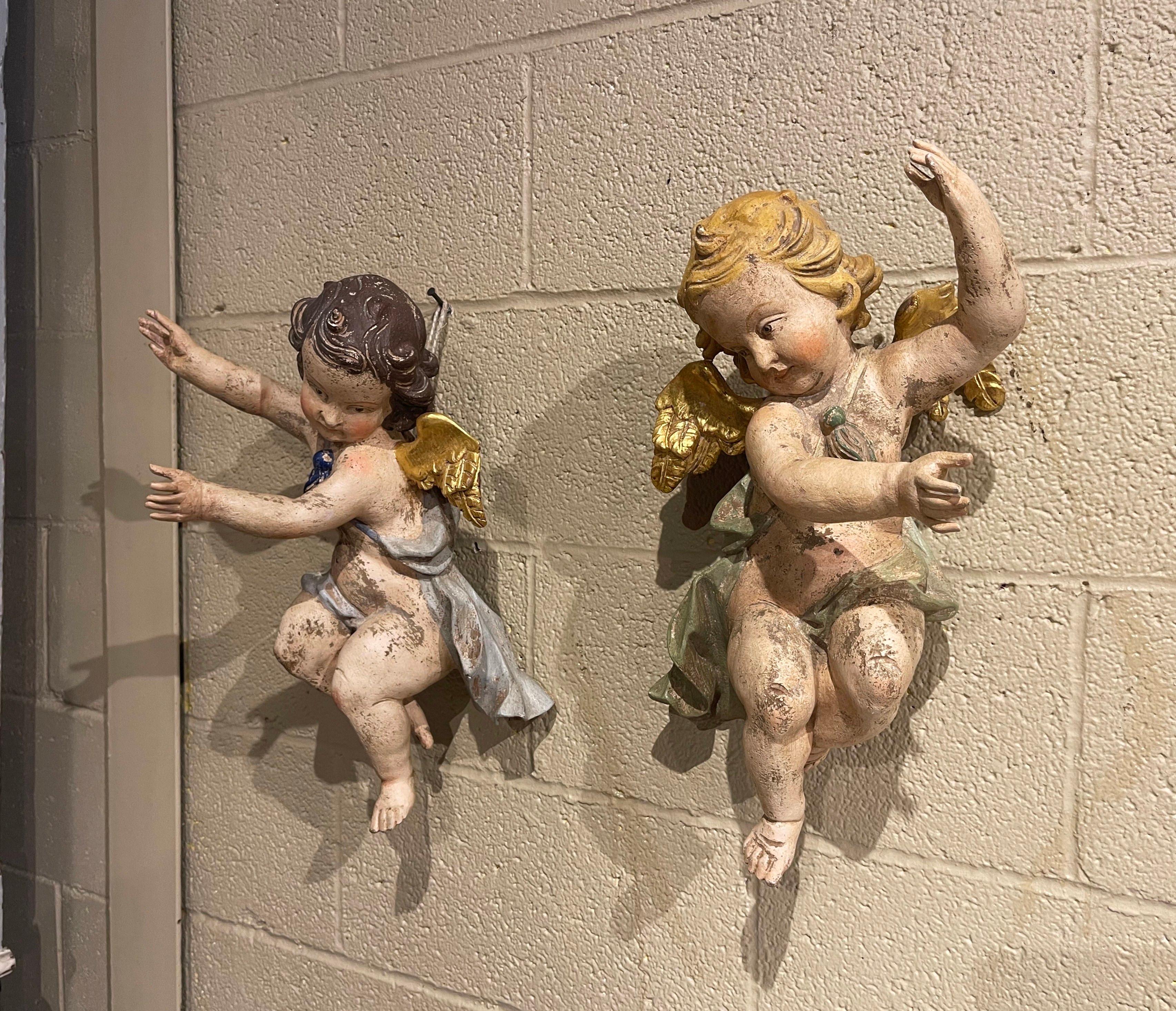 These hand carved winged cherub figures were crafted in Italy, circa 1880. The hand-painted putti carvings feature their original polychrome and gold leaf finish for a luxurious result. The colorful cherubs are expressive in their movement and