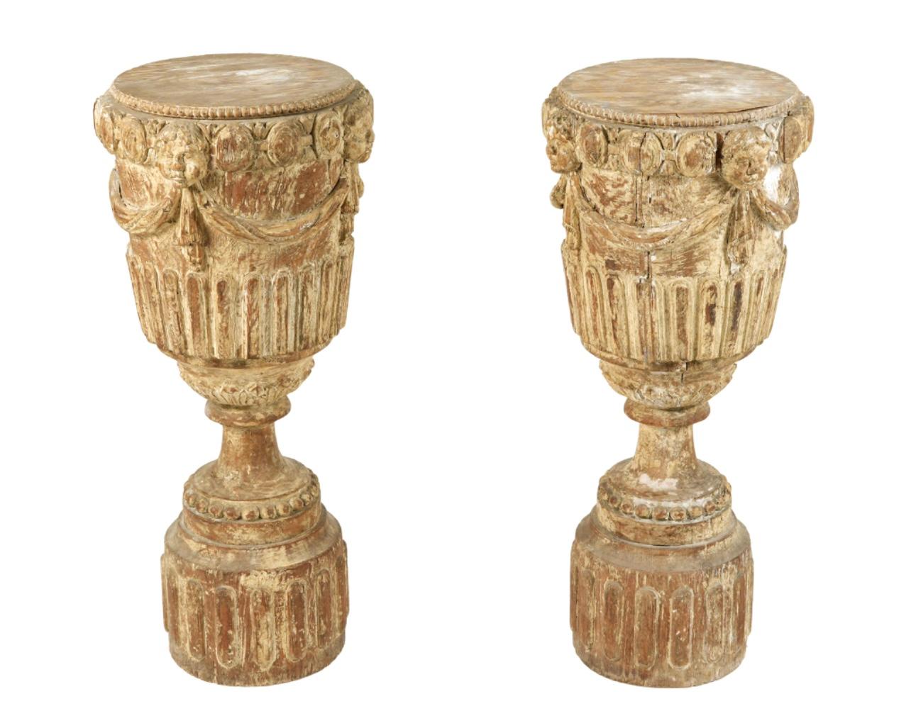 Pair of beautifully crafted 19th century Italian carved wood pedestals. Pedestals feature urn form tops with wonderfully carved tapestry swags, cherubic masks, and fluted lower section on a round base. Worn to the perfect patina these would be ideal