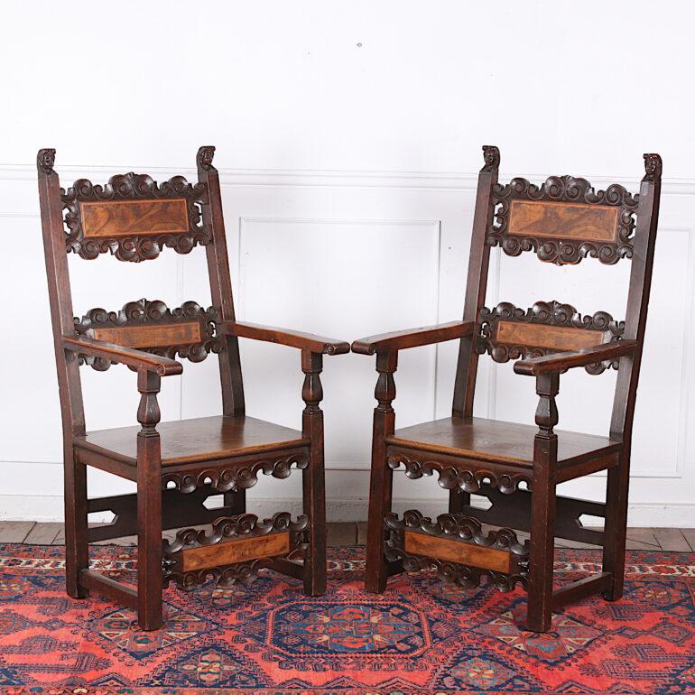 Pair of Italian carved and inlaid armchairs the backs with burl walnut panels framed with carved scrolled details and boxwood inlay, the front legs joined with a stretcher of the same design. Small carved faces on the top of the back uprights, circa