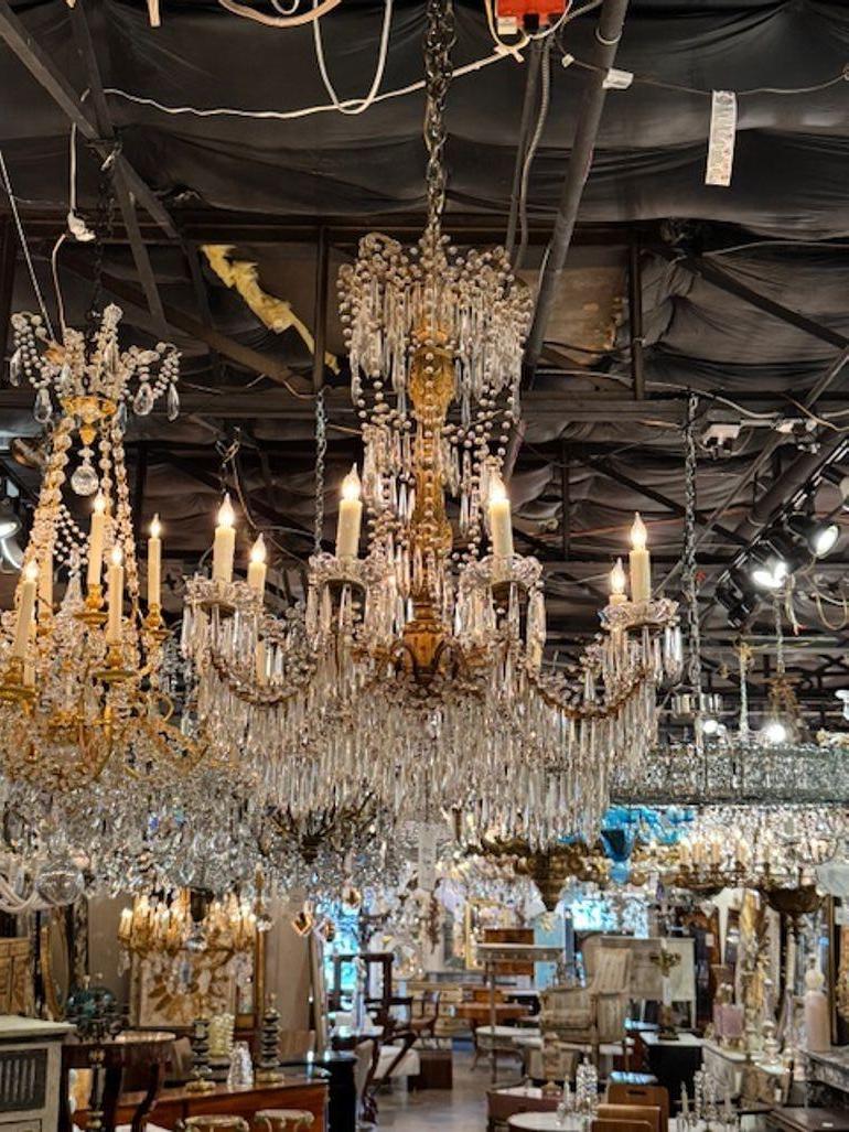 Dies ist ein Paar italienischer Kronleuchter aus Goldholz und Kristall aus Genua aus dem 19. Die Kronleuchter zeichnen sich durch ein luxuriöses Design mit aufwändigen Vergoldungsdetails und funkelnden Kristallen aus und spiegeln die Eleganz und