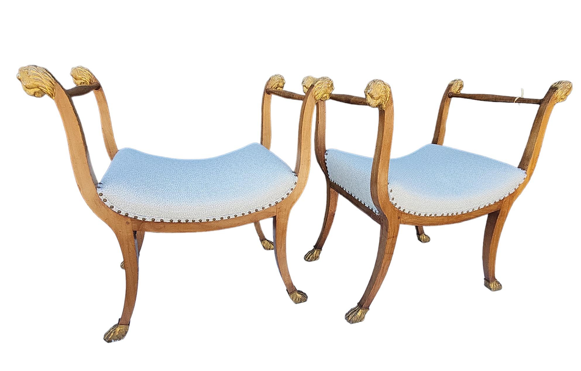 Paire de bancs (tabourets) italiens à poignées, avec pieds poilus dorés et détails en forme de tête de lion.  Le siège a été récemment recouvert d'un tissu Janet Yonaty dans un ton blanc cassé avec des fils d'or qui traversent le tissu.  Solides et