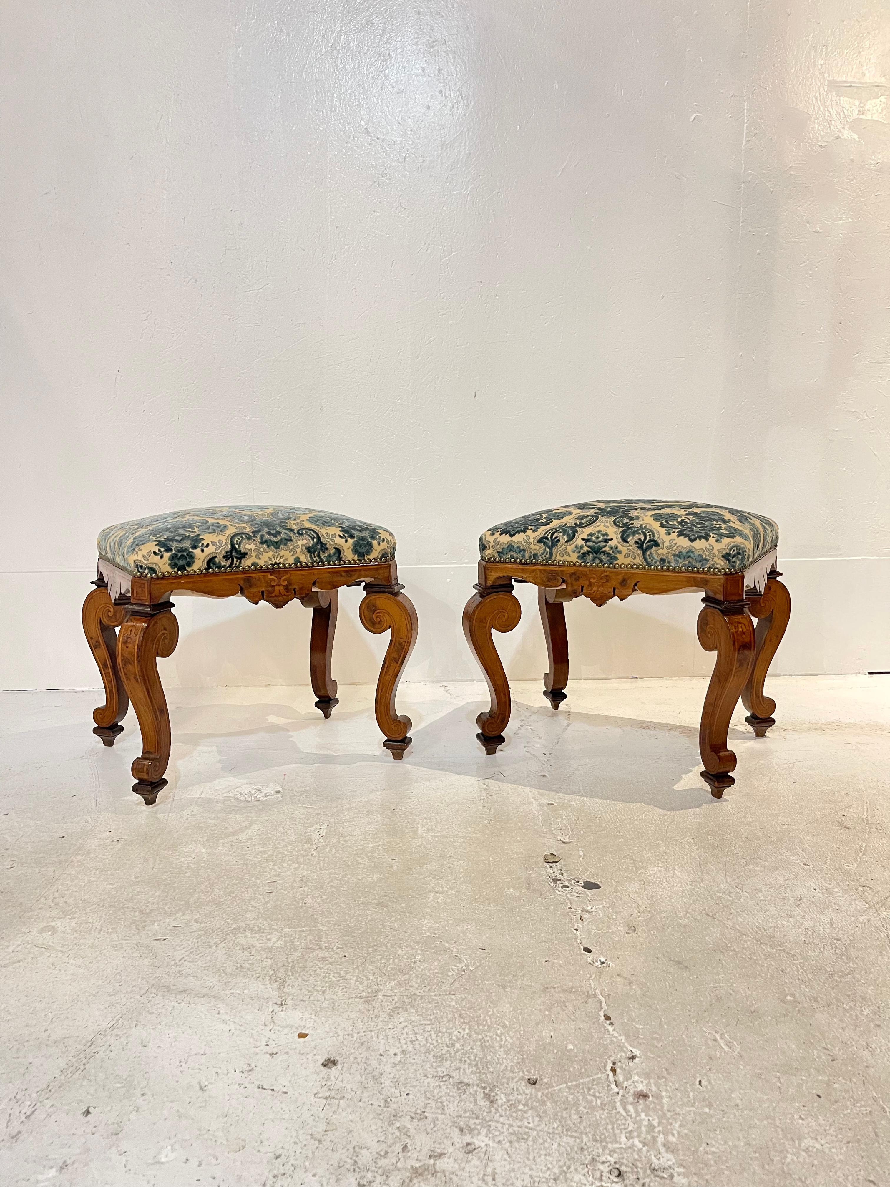 A rare pair of early 19th century Italian burl walnut stools designed in the style of Rococo. Recent upholstery of the seat can be seen in a blue and cream cut-velvet damask embellished with nailhead trim. Beneath the seat, an apron is carved of