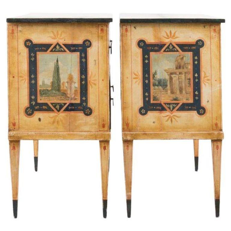 Pair of Italian Neoclassical wooden two-drawer commodes made in the 19th Century with polychrome painted mythical figures around gracefully adorning the surfaces. These each include a faux marble top with beautiful green and blue