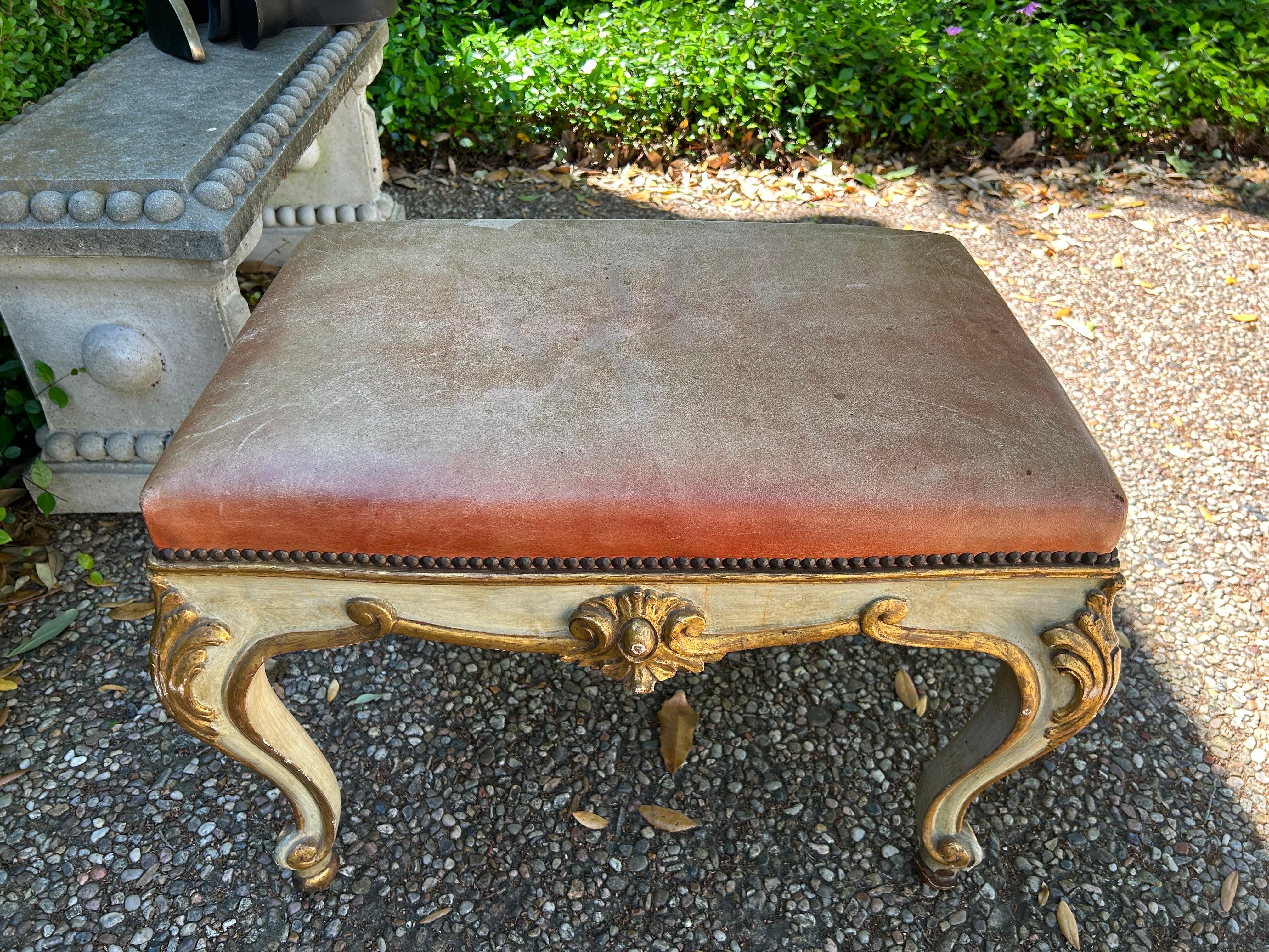Pair Of 19th Century Italian Painted And Parcel Gilt Ottomans.
This pair of antique Italian Regence style painted and gilt ottomans or benches are currently upholstered in distressed leather with nail head detail, but easily reupholstered in the