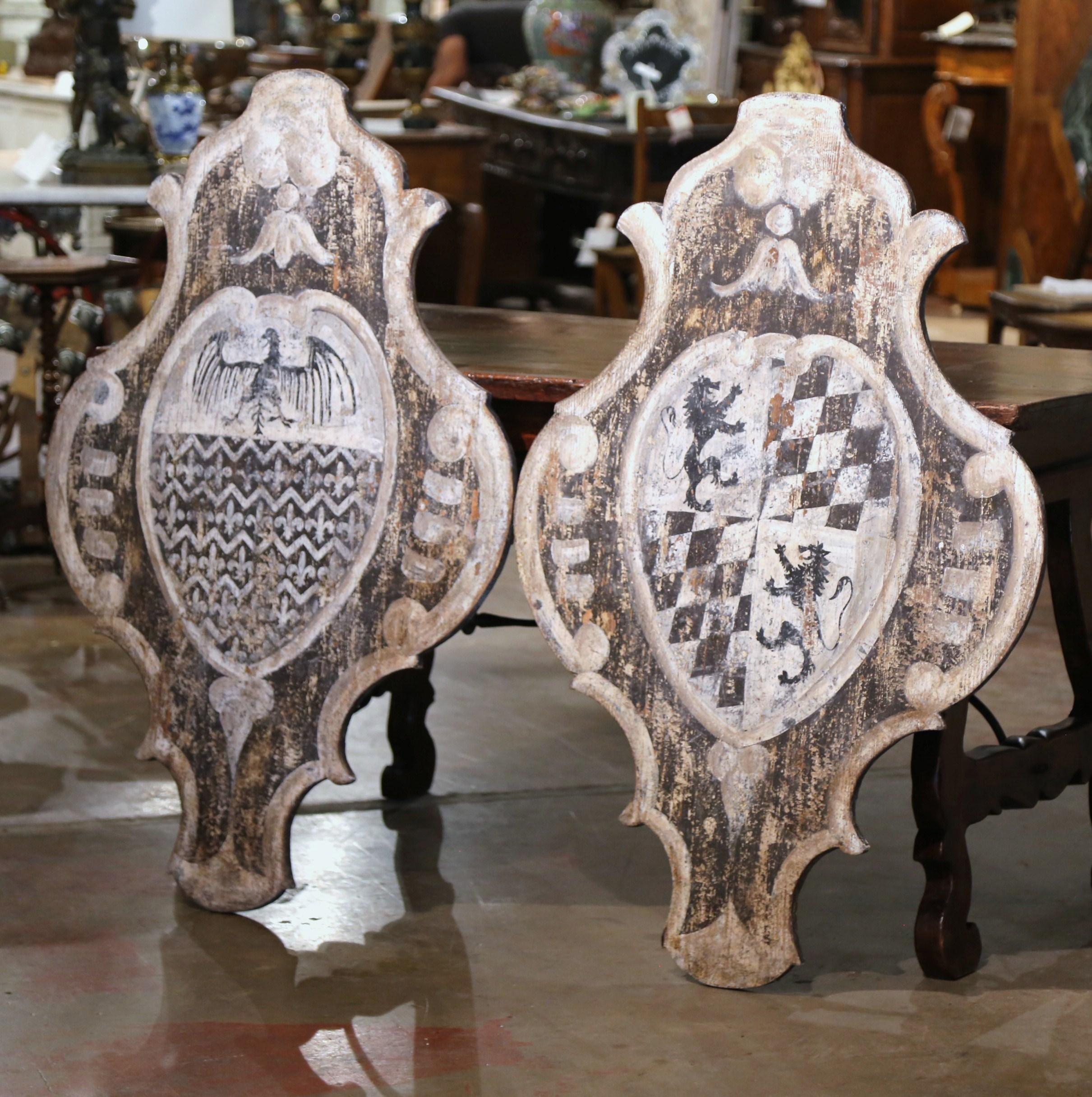 Embellish your study or library with this elegant antique pair of wall hanging plaques. Carved in Italy, circa 1880, each plaque is oval in shape with scalloped and curved edges, and depicts a family crest. One features a central medallion decorated