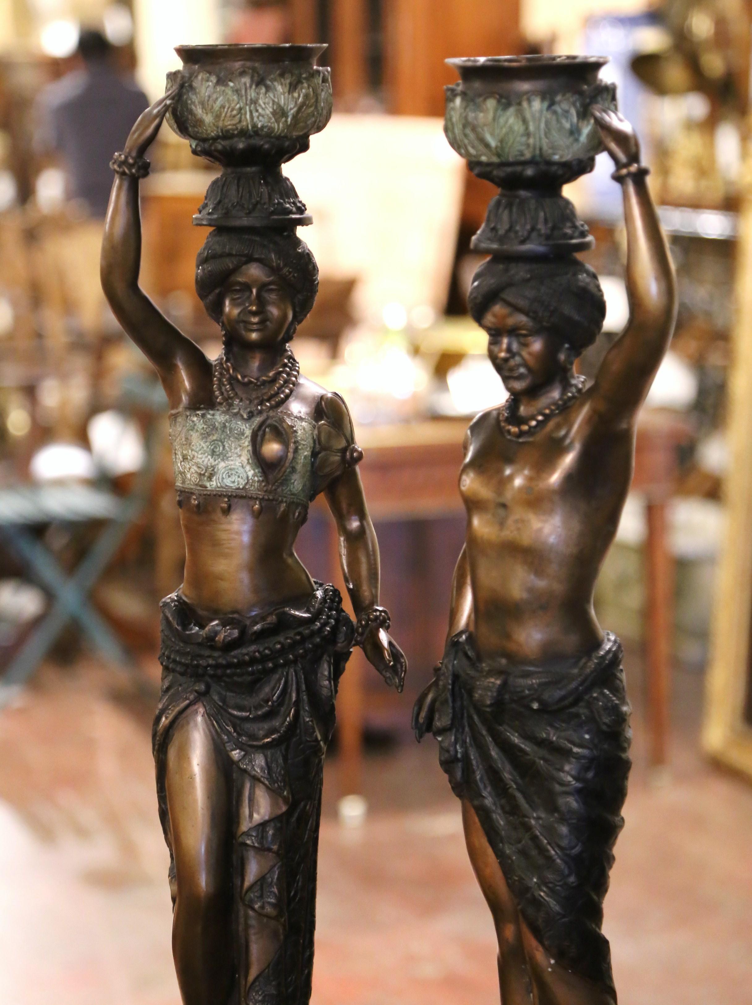 Decorate a mantel or a console with this pair of tall figurine candle holders. Crafted in Italy circa 1880 and made of bronze, each candlestick stands on an integral base with curved feet decorated with leaf motif over a scalloped apron. Each statue