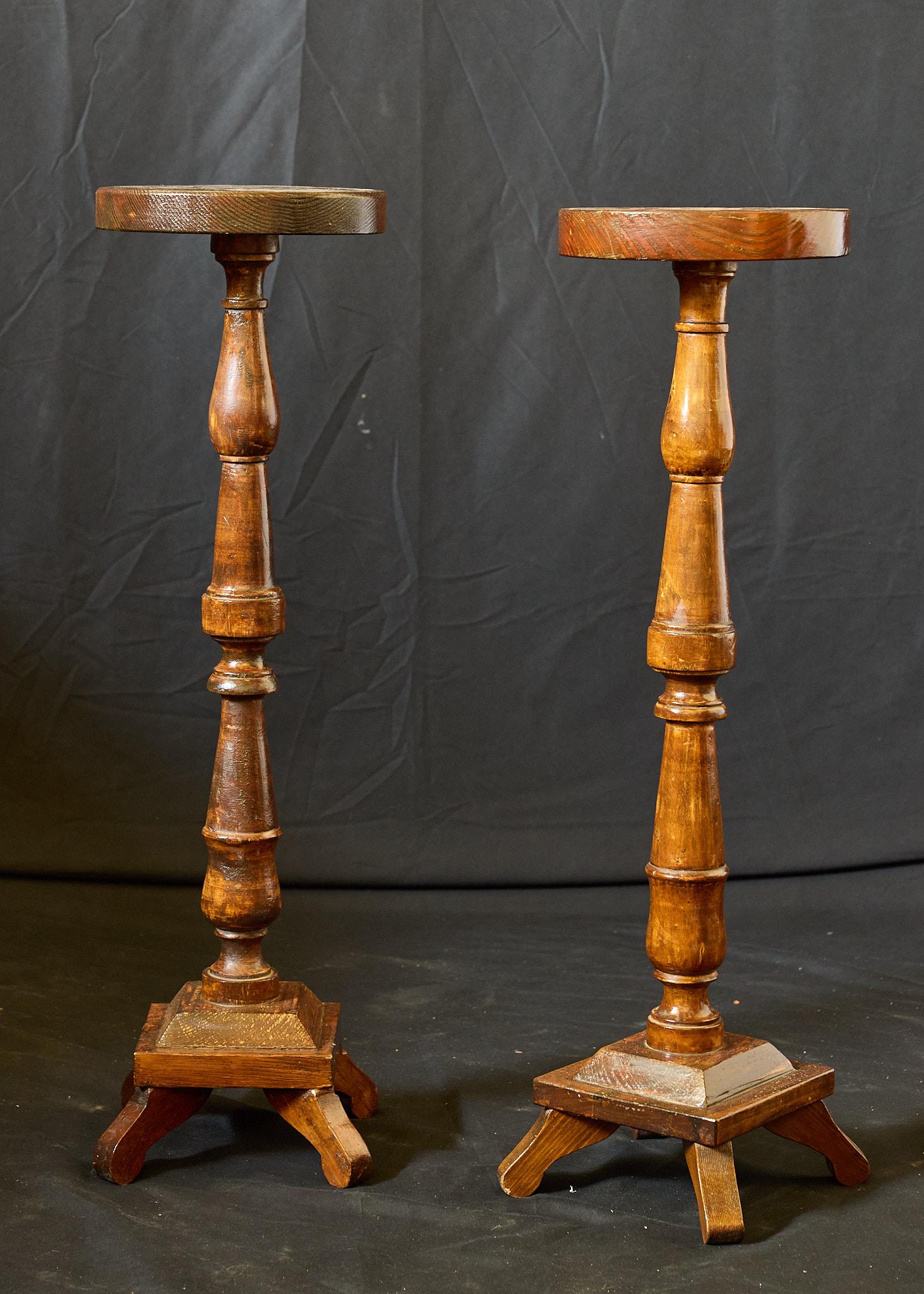 Charming antique pair of Neoclassical style Italian fern or plant stands made of pine with a round top, a turned pedestal, and a square stepped pyramidal platform base raised on a stylized scroll foot.  Late 19th Century. 

Solid and sturdy