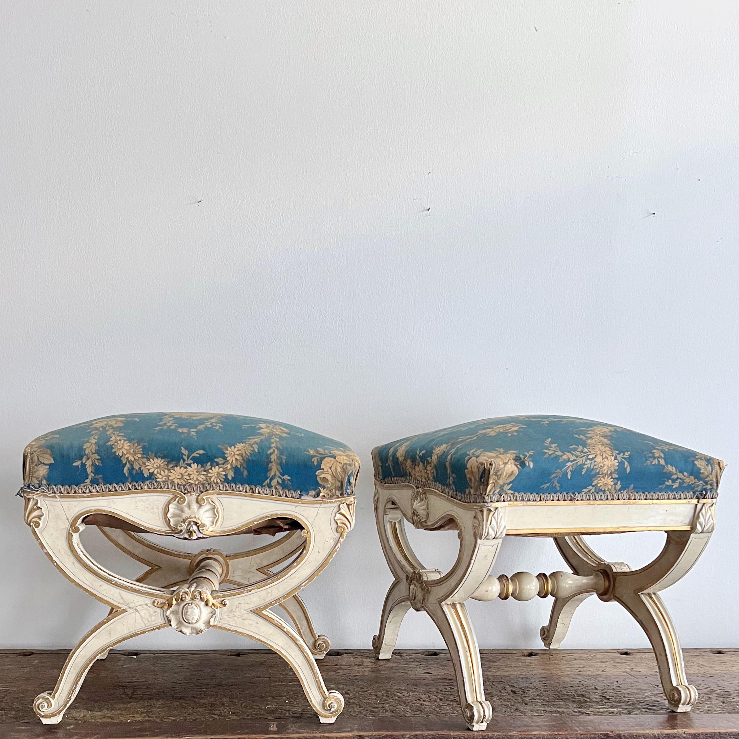 Pair of 19th century Italian painted and gilt wood curule stools with richly carved medallions, resting on scrolled feet with cross stretchers. 
Uphlostered in original timeworn Italian fabric. 